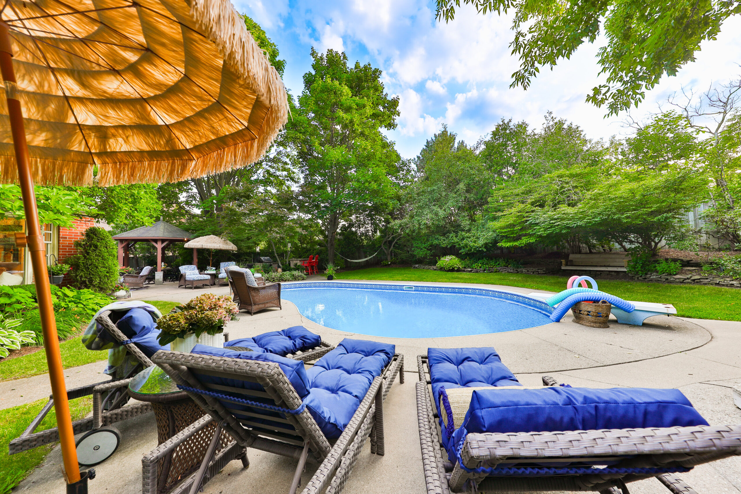 Backyard pool area with lounge chairs and a thatched umbrella