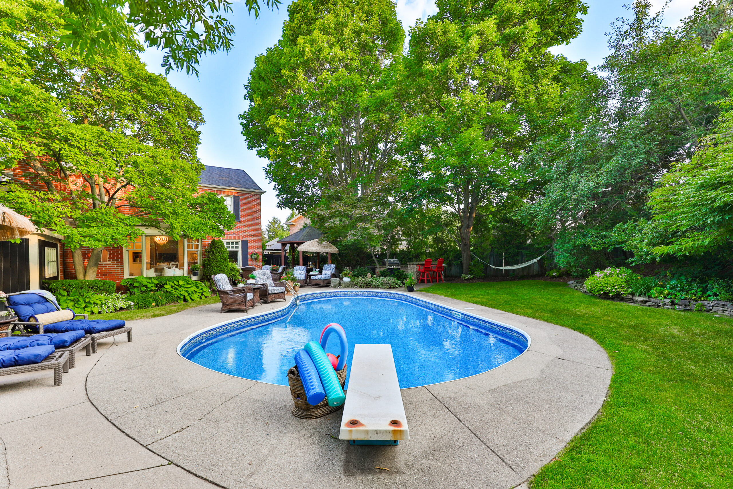 Backyard pool area with lounge chairs and lush greenery