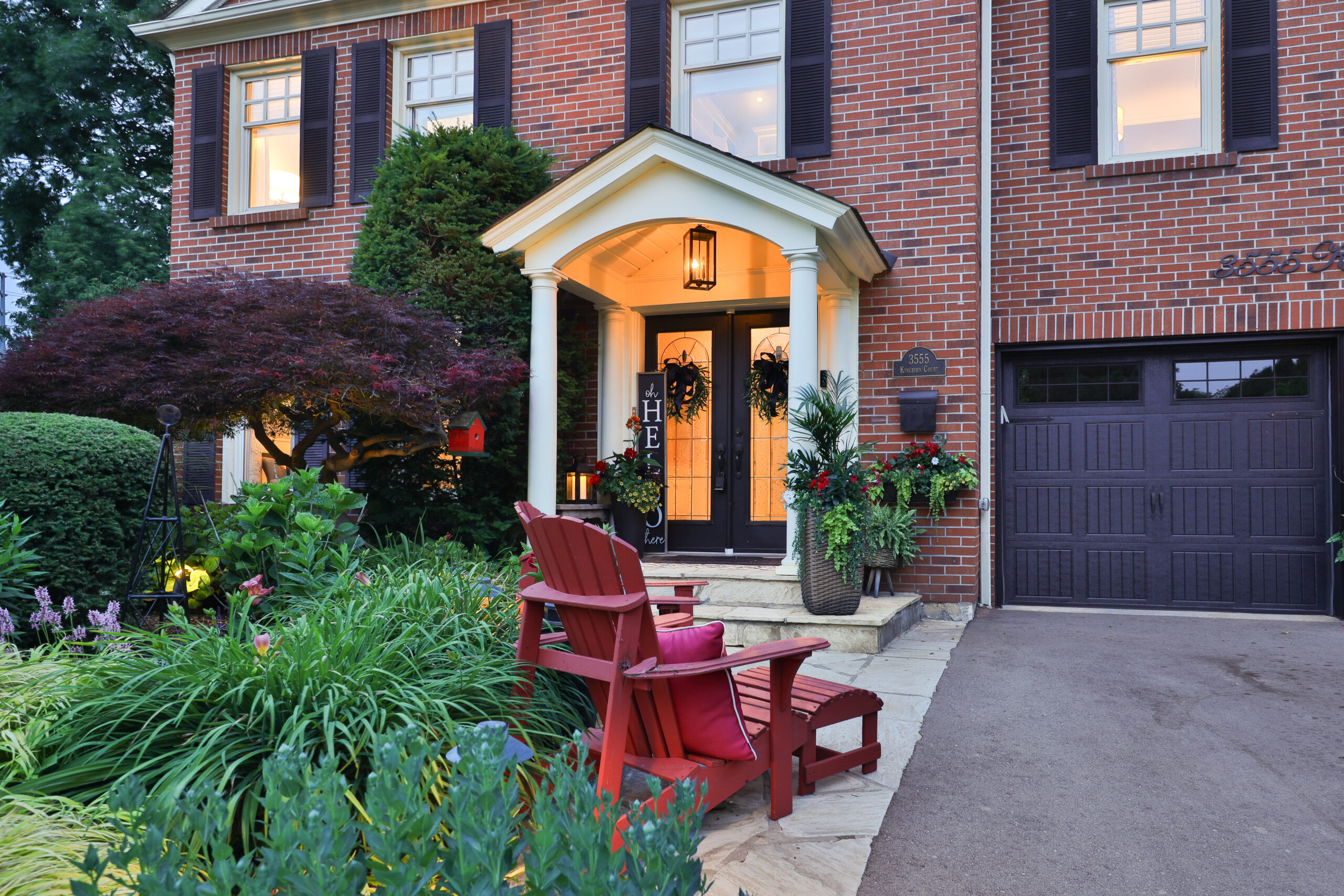 Charming brick house entrance with red chairs and lush garden plants