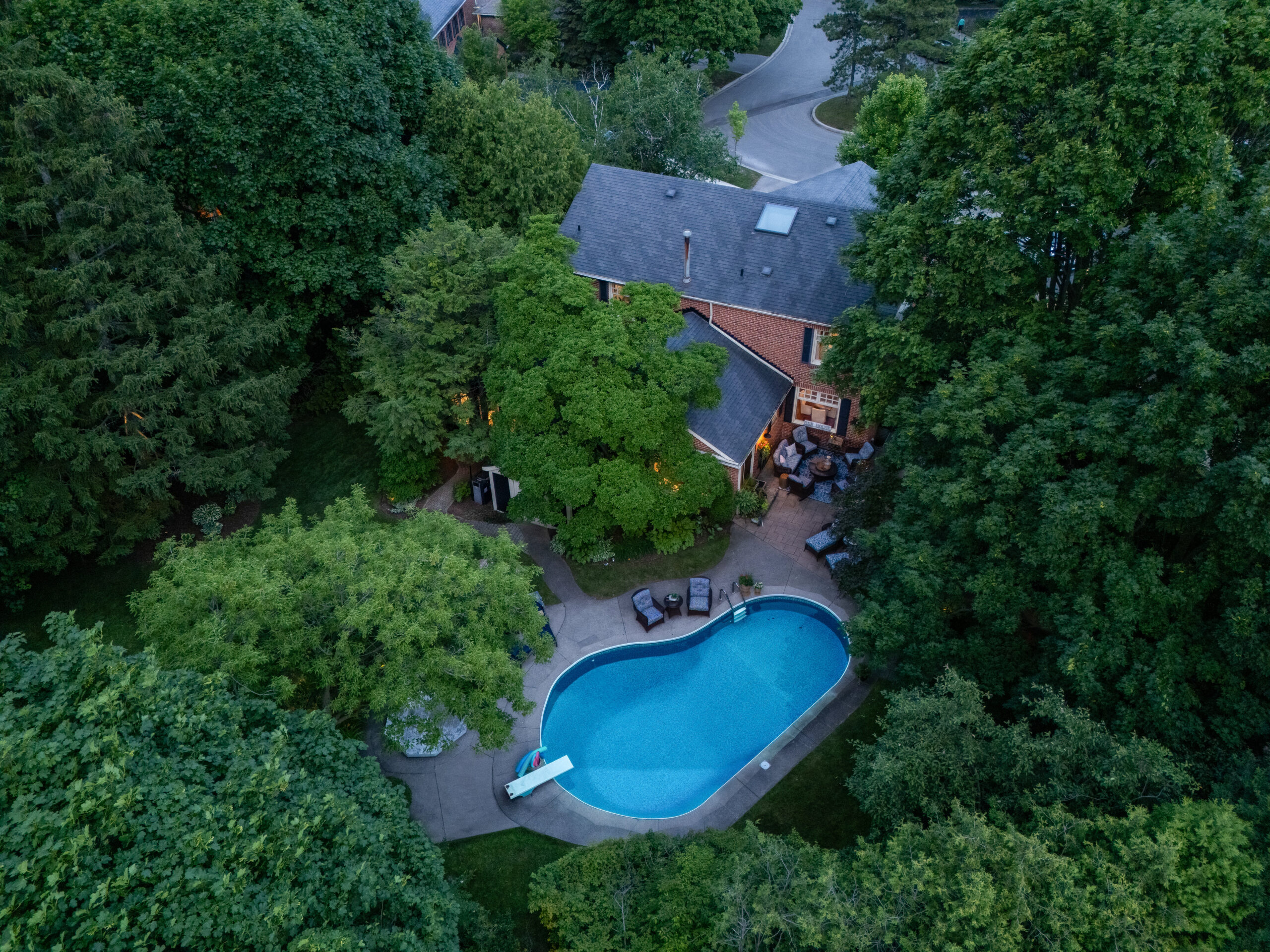 Aerial view of a house surrounded by trees with a swimming pool in the backyard