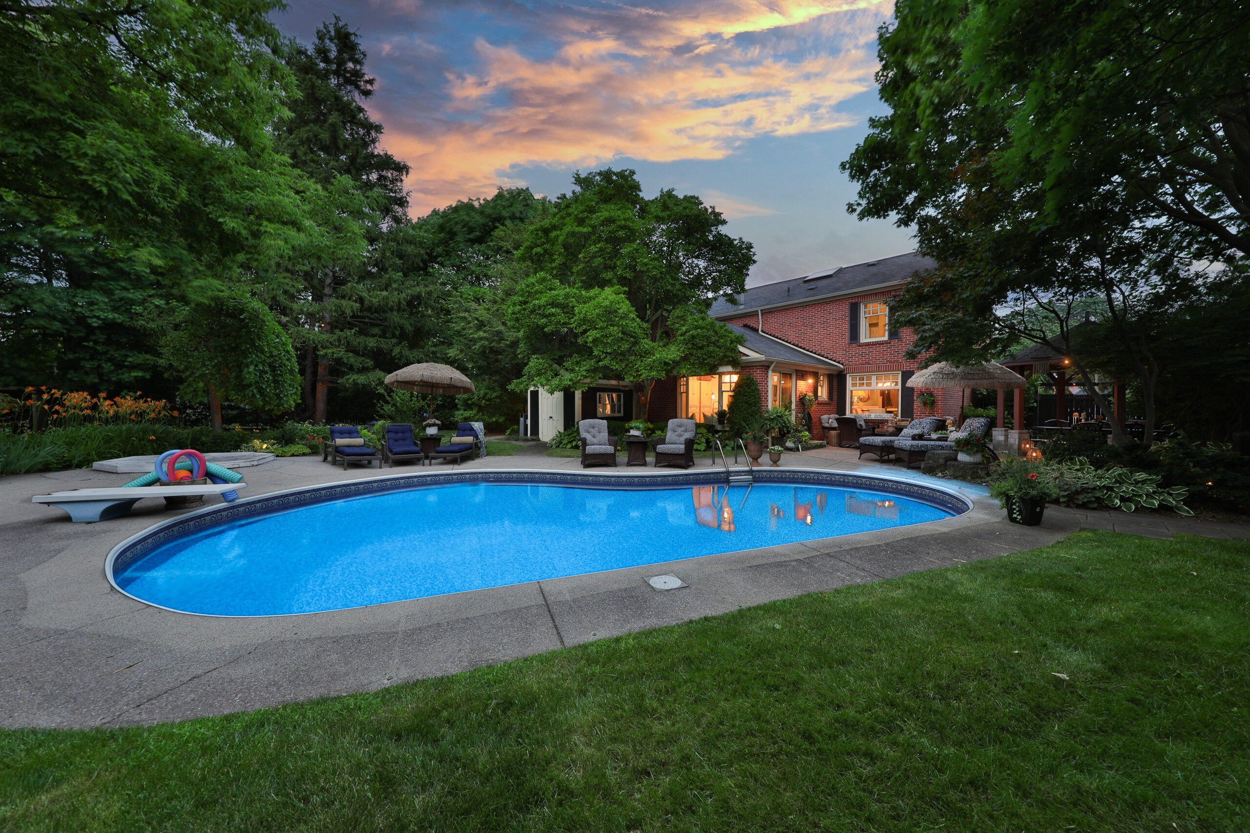 Backyard pool area with lush greenery and sunset sky at Kingbird Court