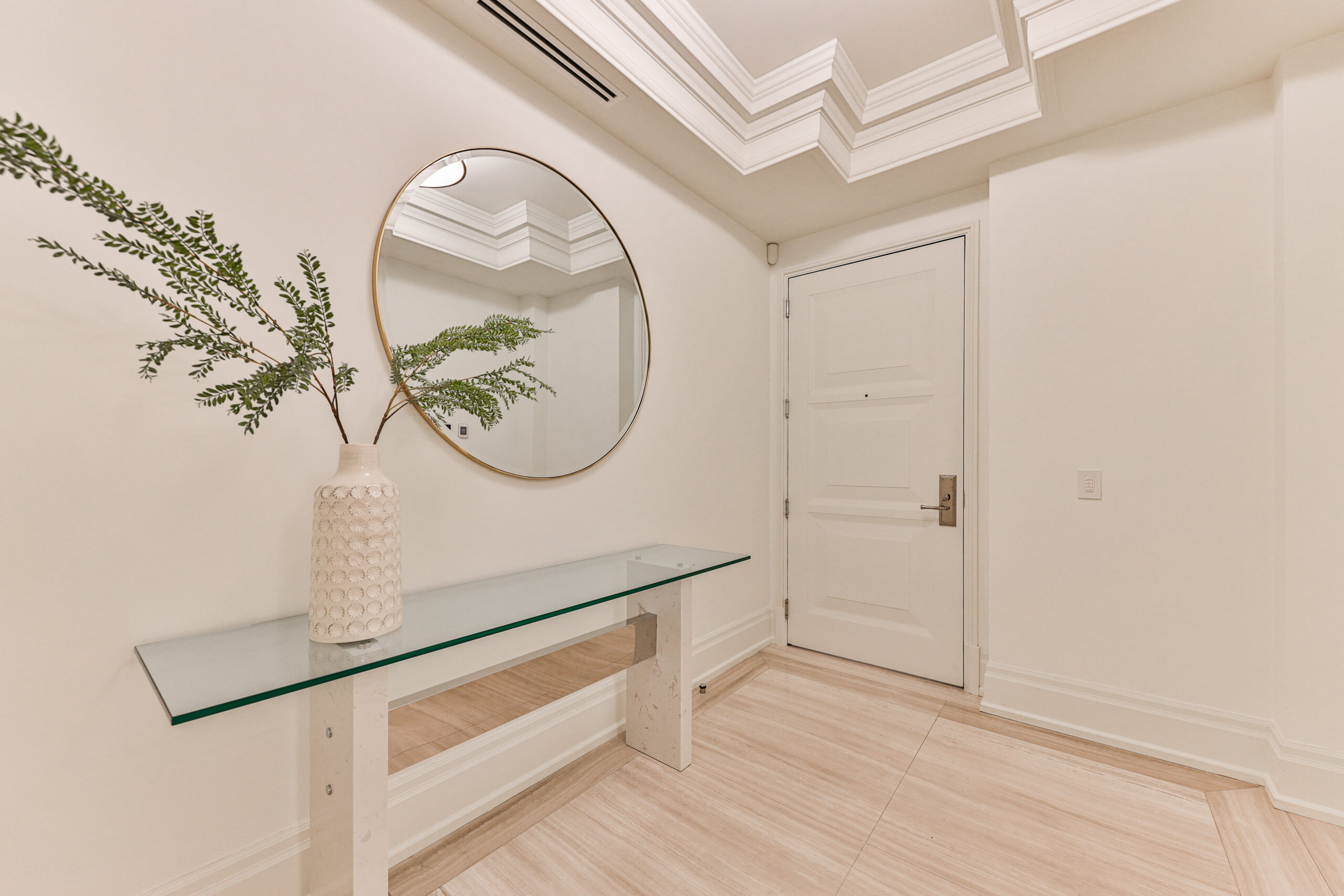 Modern entryway with a round mirror and glass console table