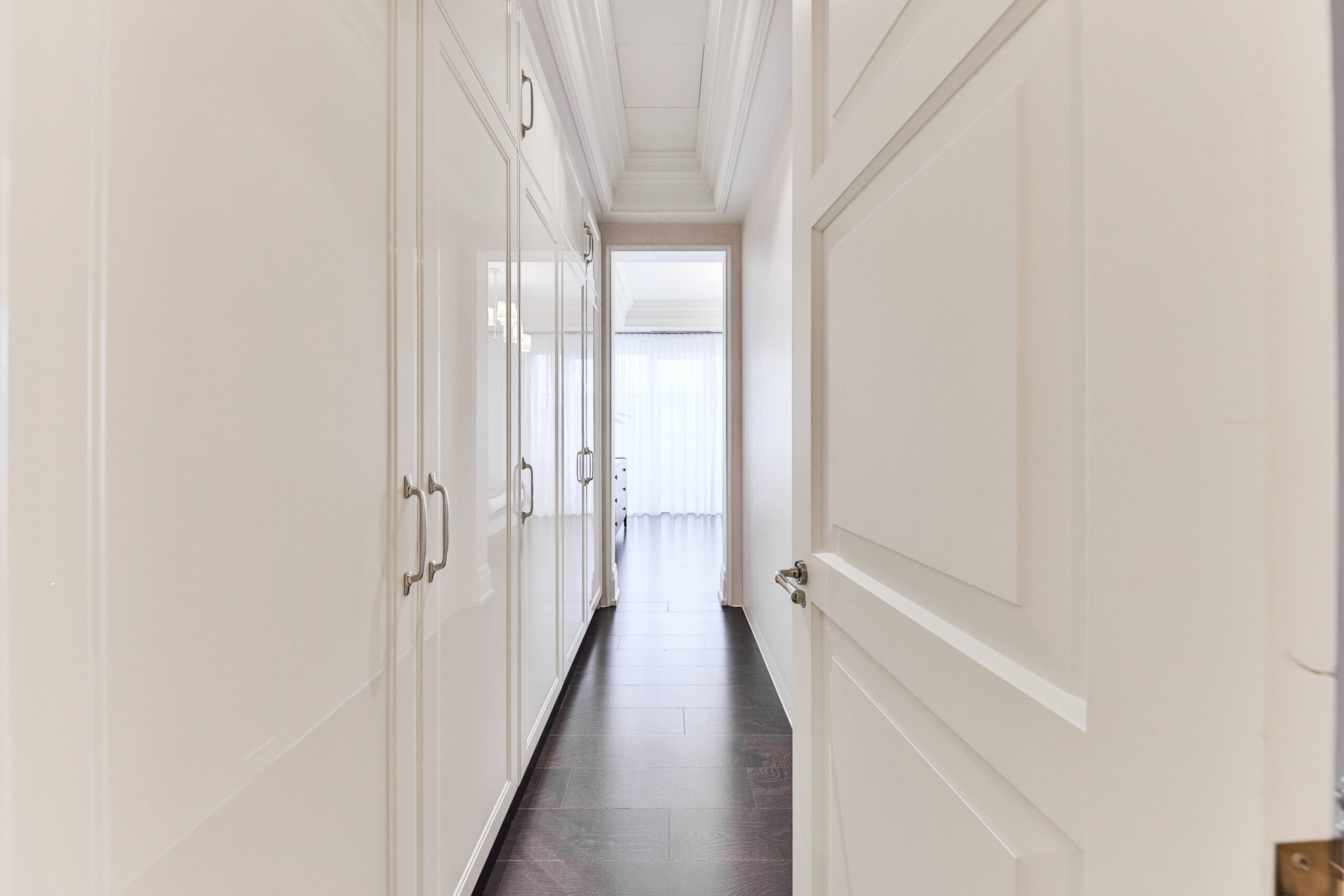 Bright hallway with white cabinetry and dark wood flooring