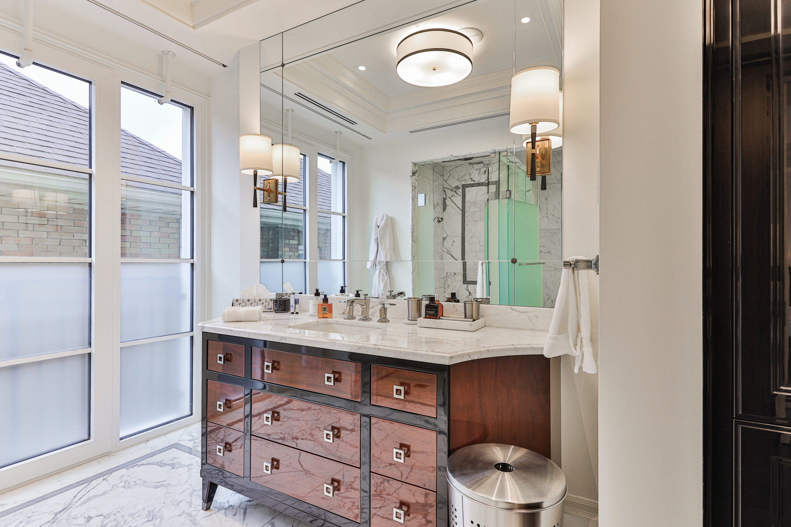 Luxurious bathroom with a marble countertop and wooden vanity, featuring large windows