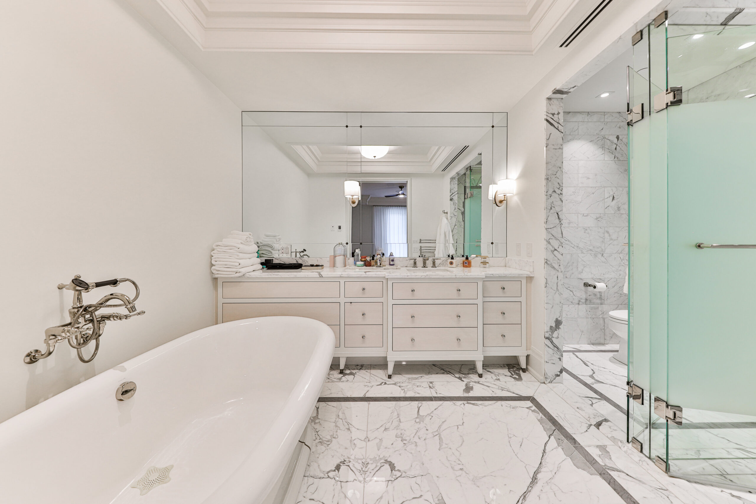 Luxurious bathroom with marble flooring, freestanding tub, and glass shower
