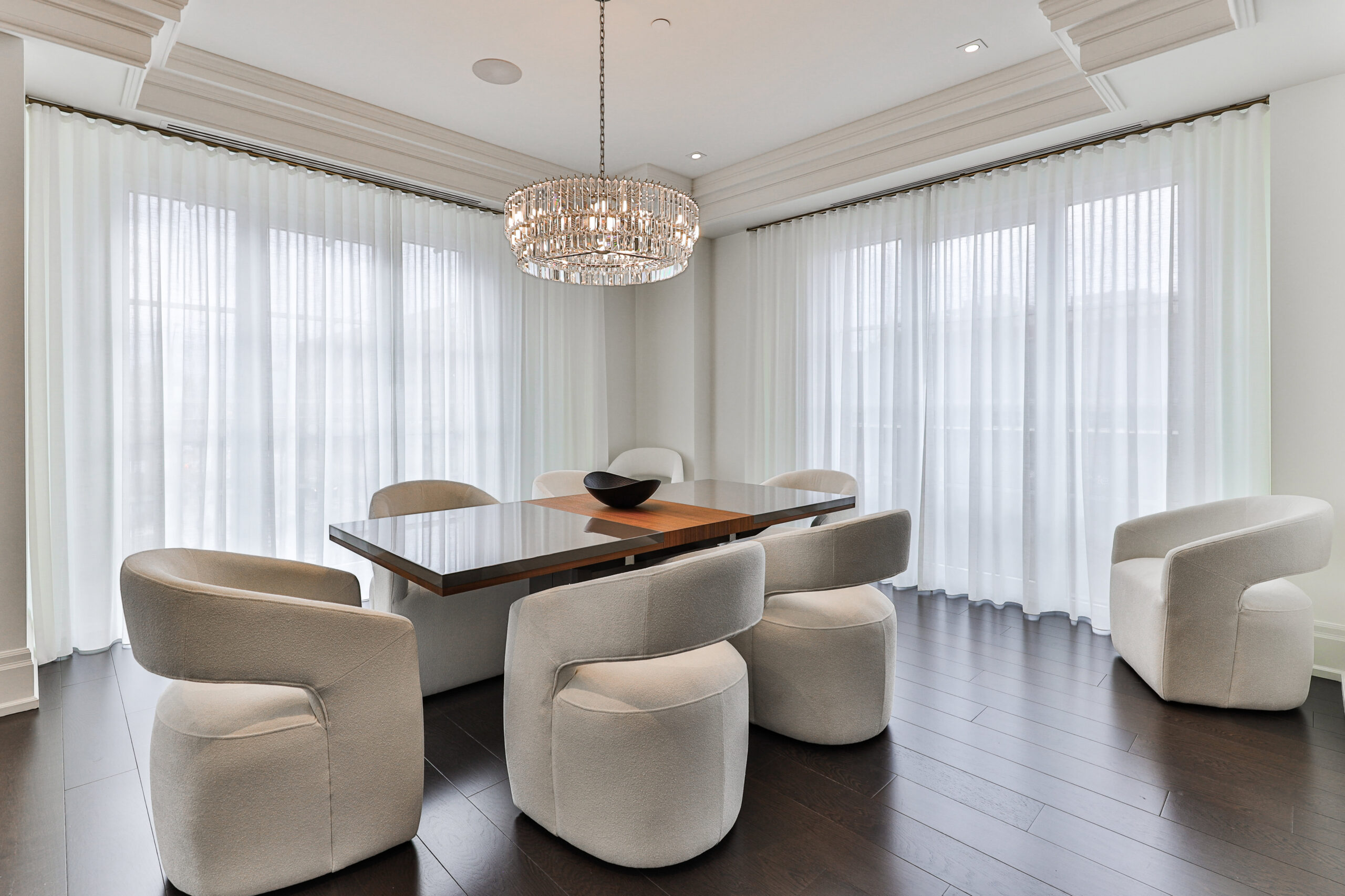 large dining room with chandelier, surrounded by windows and custom curtains