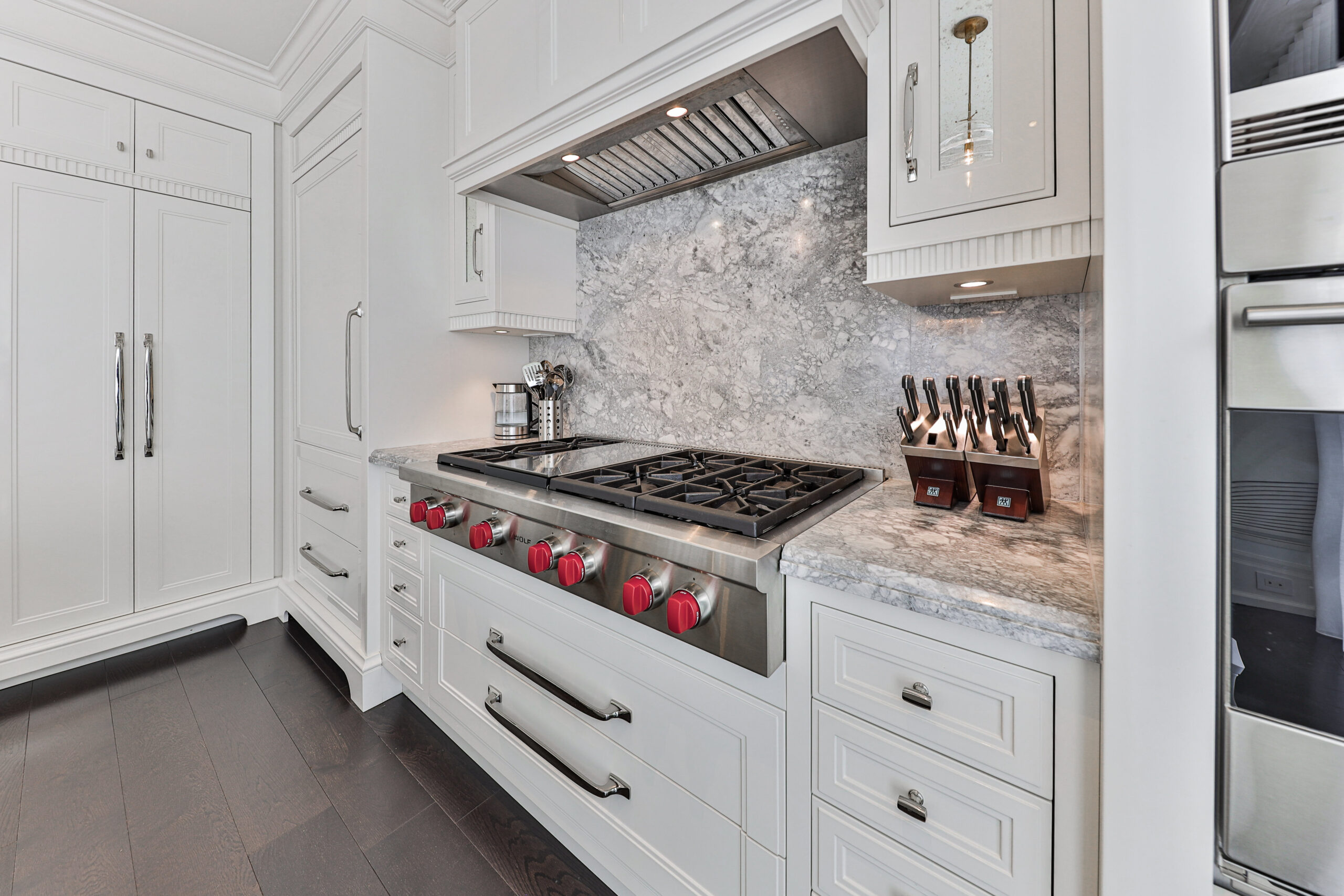 Modern kitchen with white cabinetry, marble backsplash, and stainless steel appliances