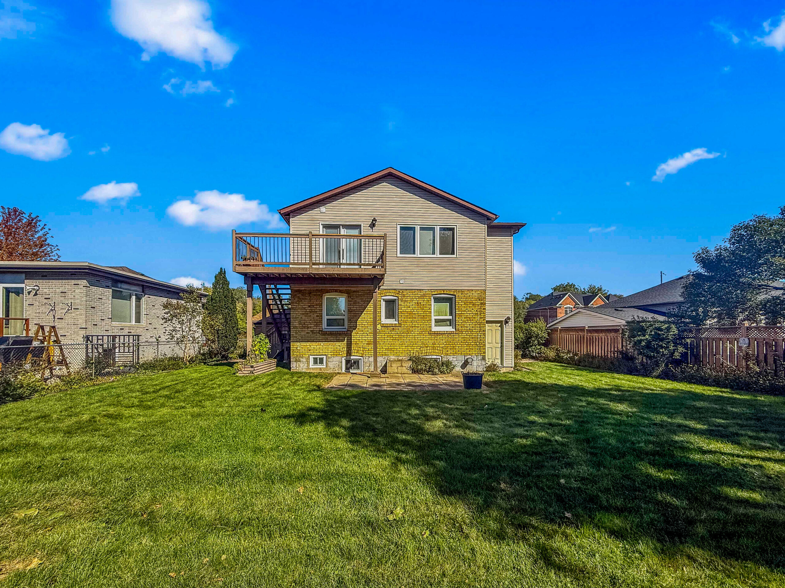 rear view of house featuring deck and large green yard