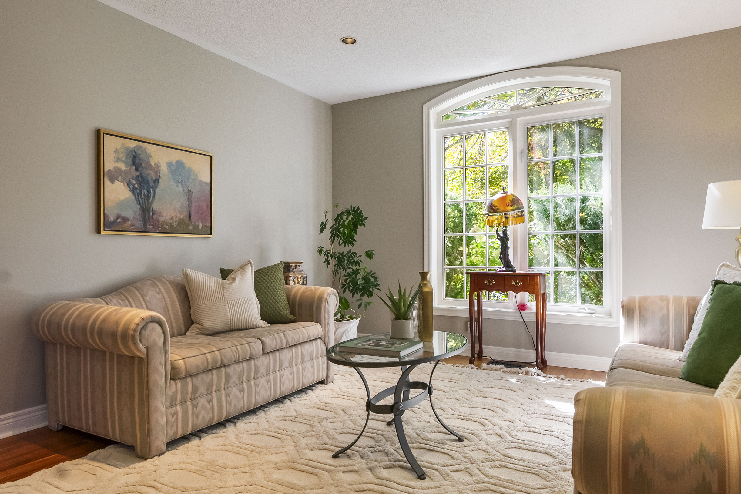 Cozy living room with beige sofas, glass coffee table, and large window