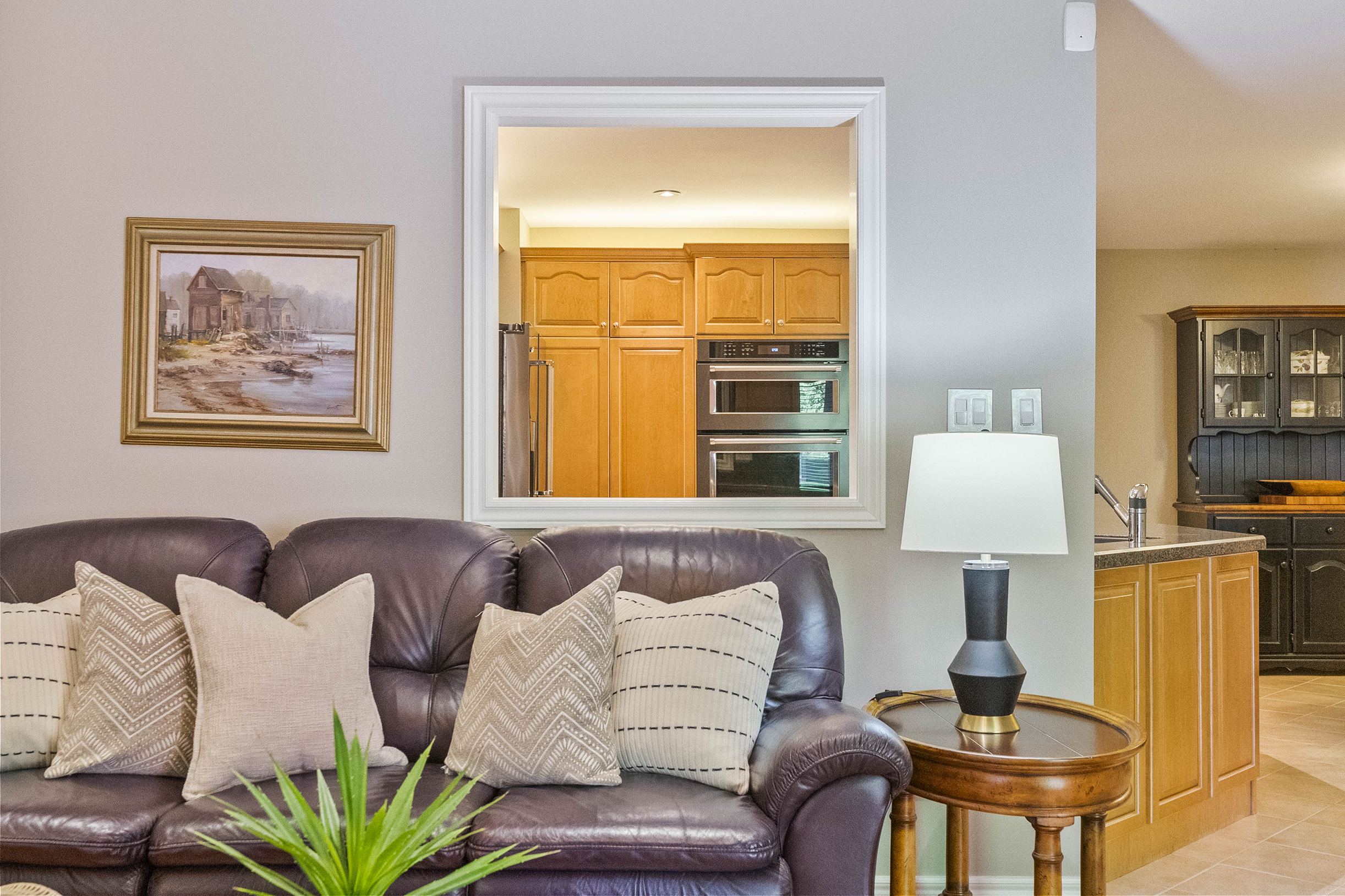 Cozy living room with leather sofa, decorative pillows, and kitchen view