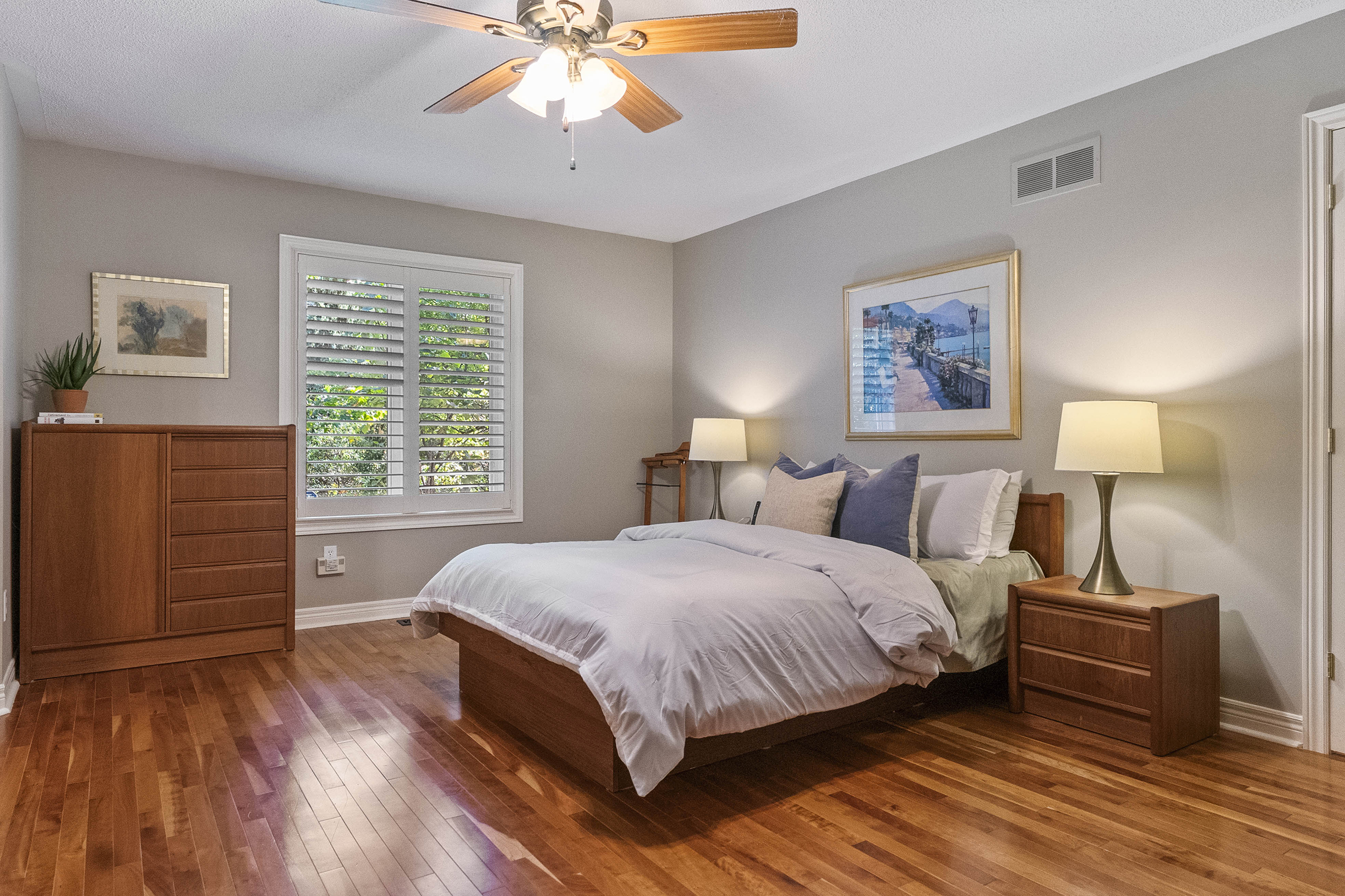 Cozy bedroom with wooden furniture, ceiling fan, and natural light