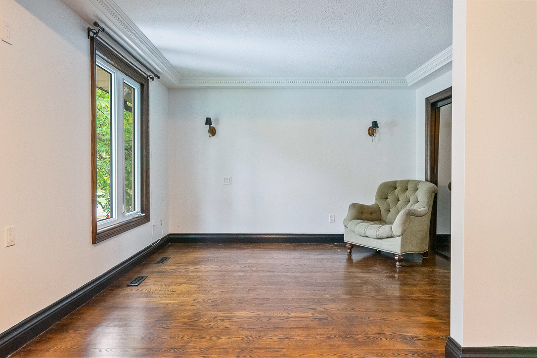 Empty living room with hardwood floor and a green armchair by the window