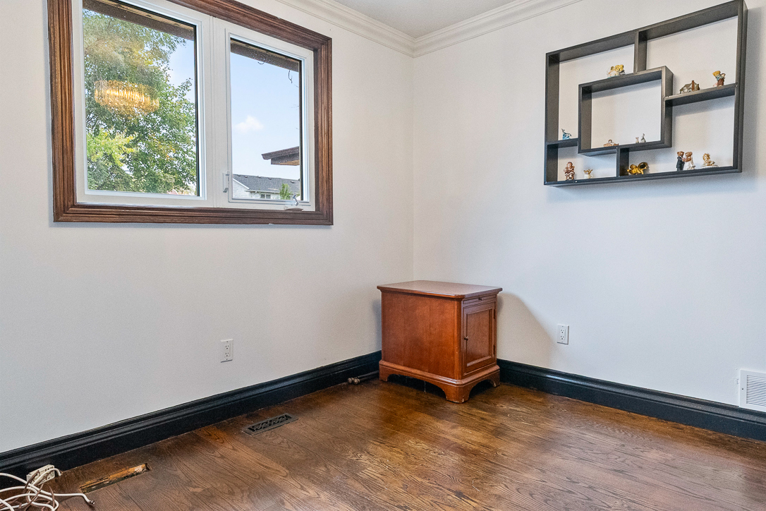 Empty room with hardwood floor, window, and wooden cabinet