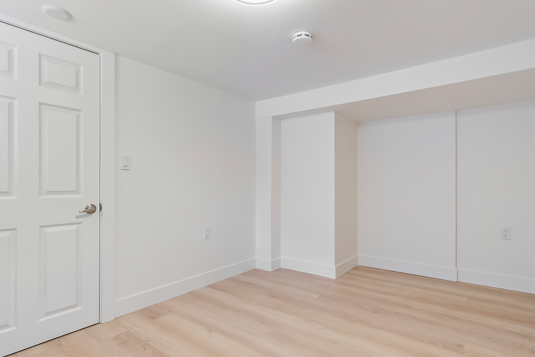 Bright, empty room with light wood flooring and white walls