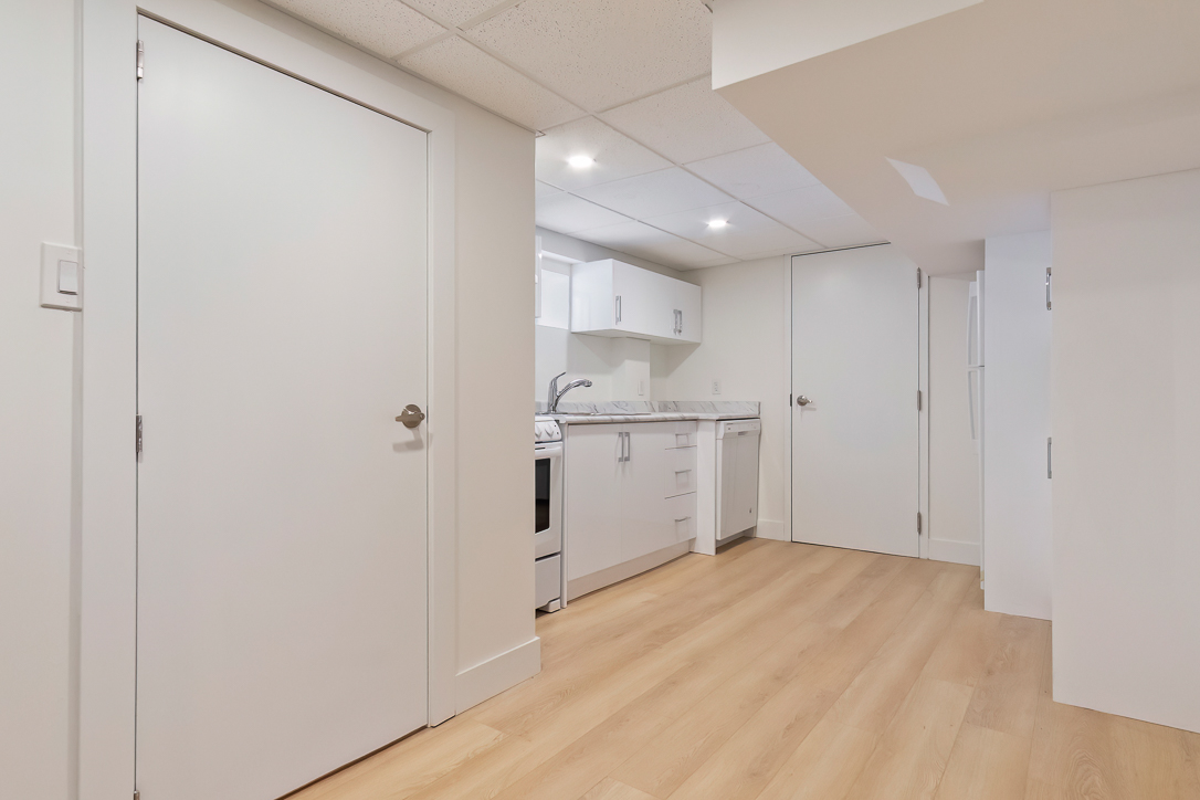 Modern kitchen area with white cabinets and light wood flooring