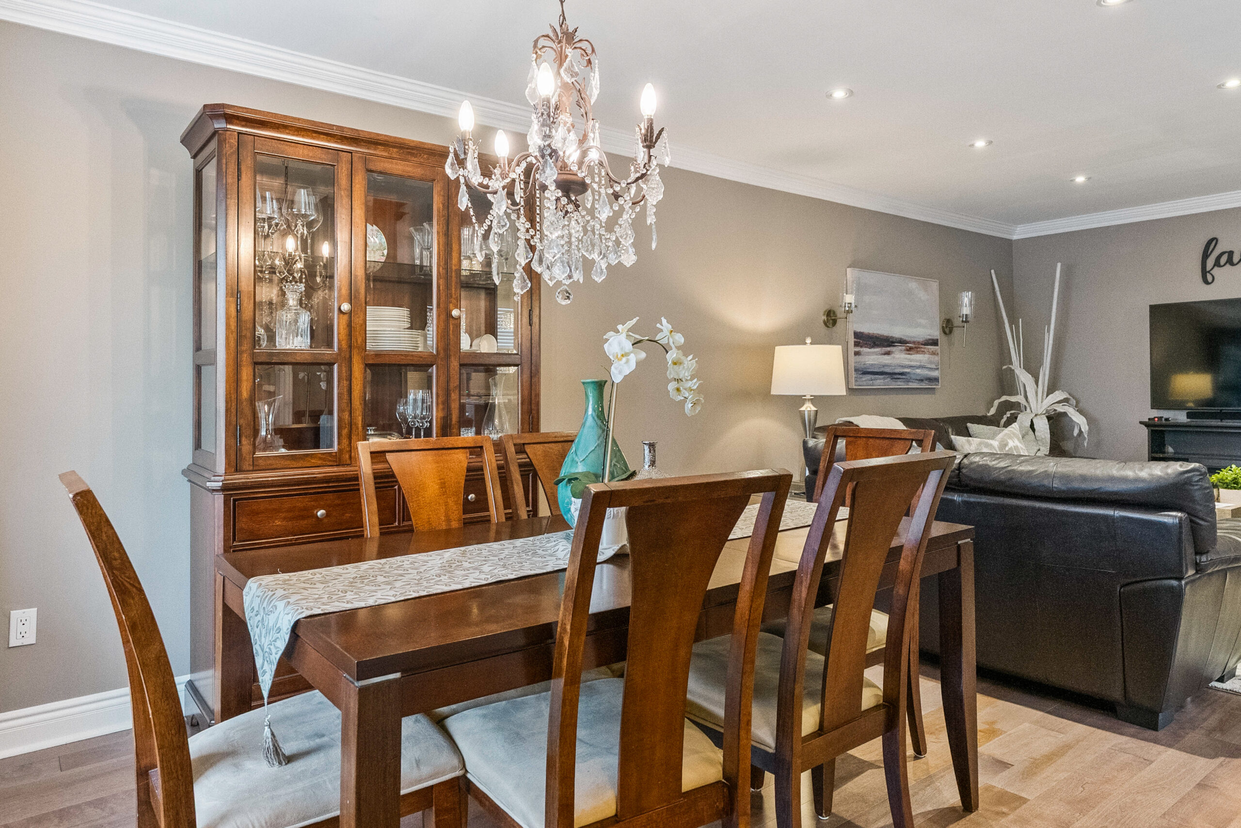 Elegant dining room with wooden table, chandelier, and glass cabinet