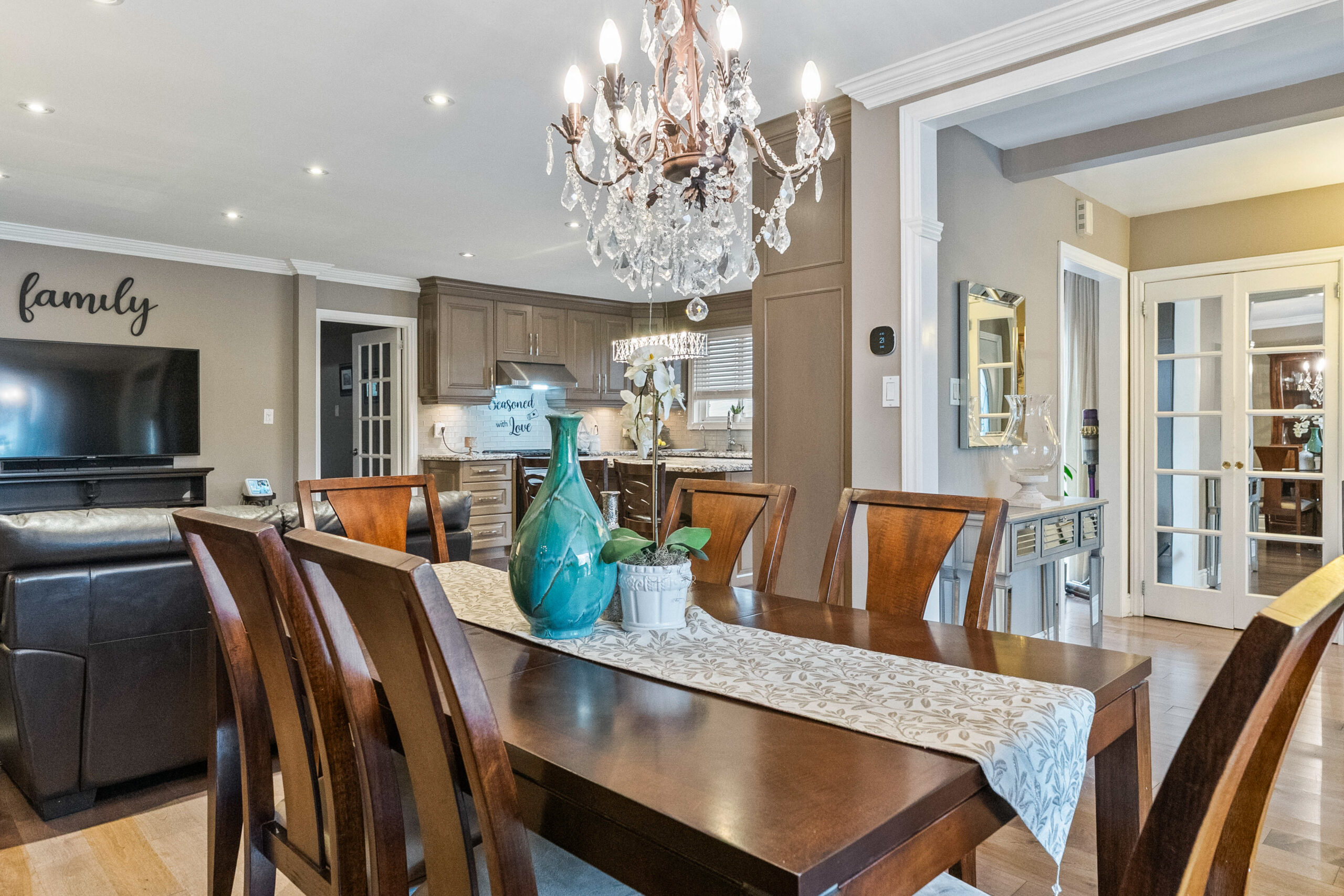 Elegant dining area with a chandelier, wooden table, and modern kitchen backdrop
