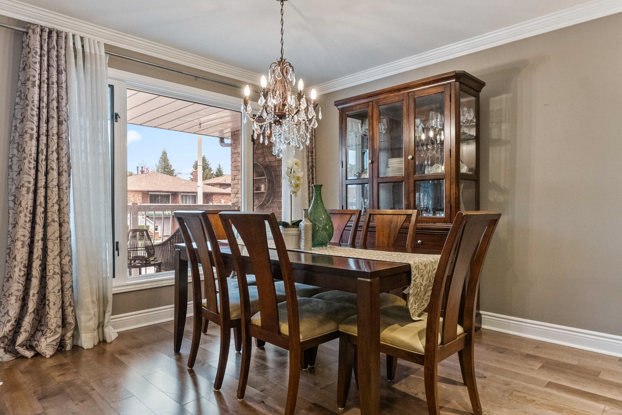 Elegant dining room with a wooden table, chandelier, and large window.