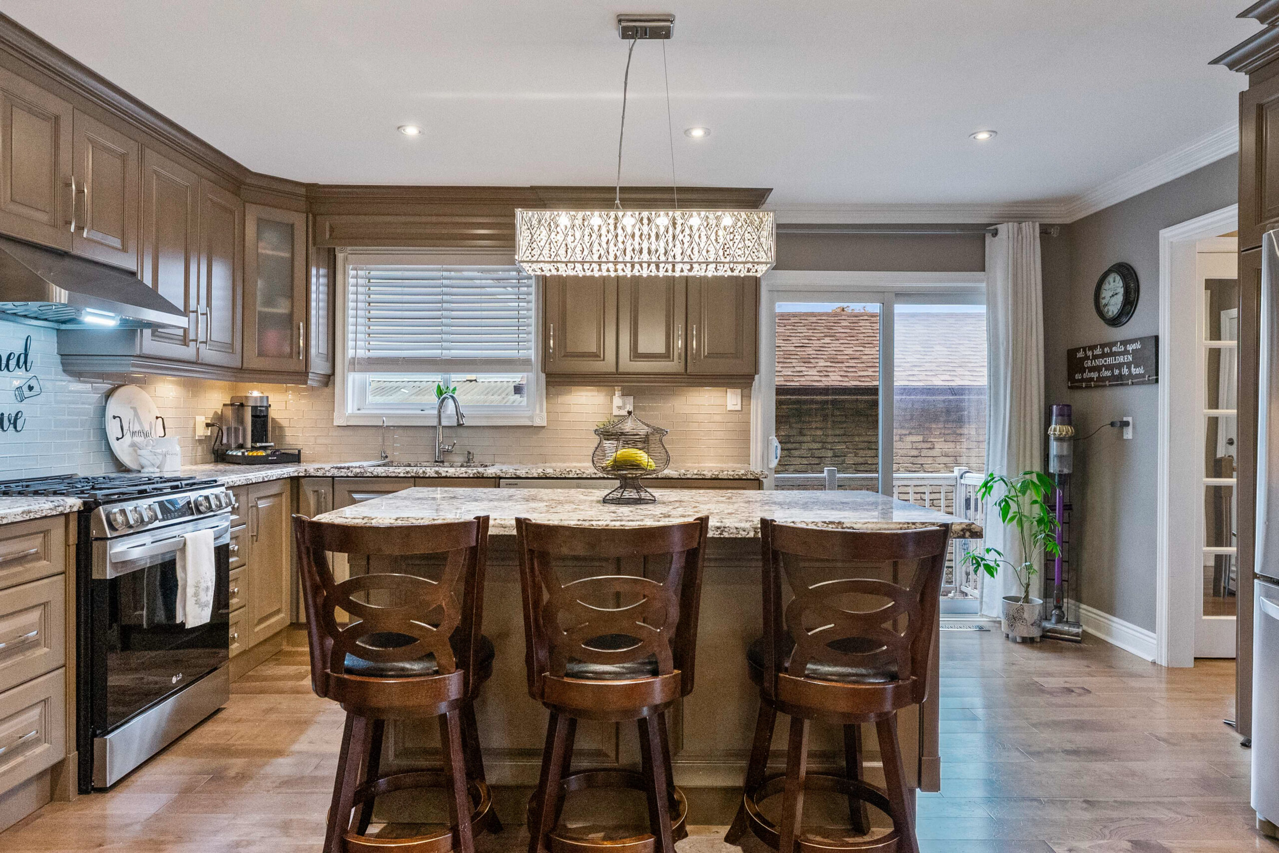 Modern kitchen with wooden cabinets, granite island, and stylish lighting