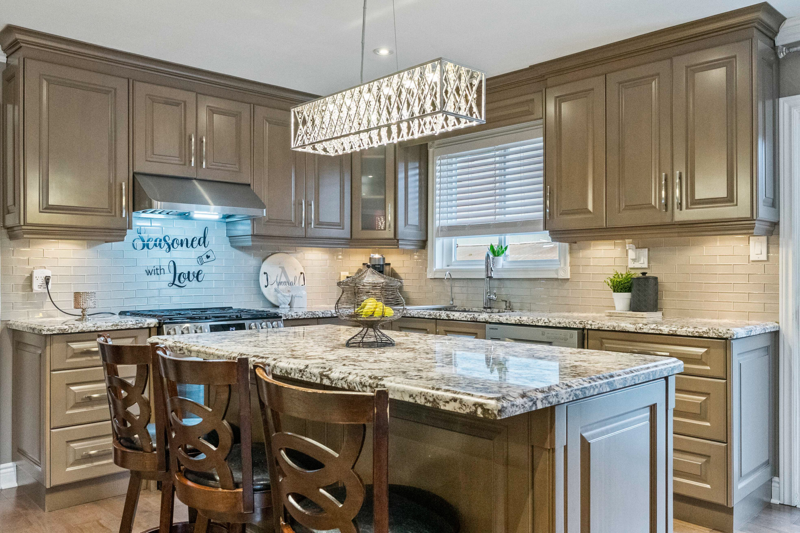 Modern kitchen with granite countertops, wooden cabinets, and stylish chandelier.