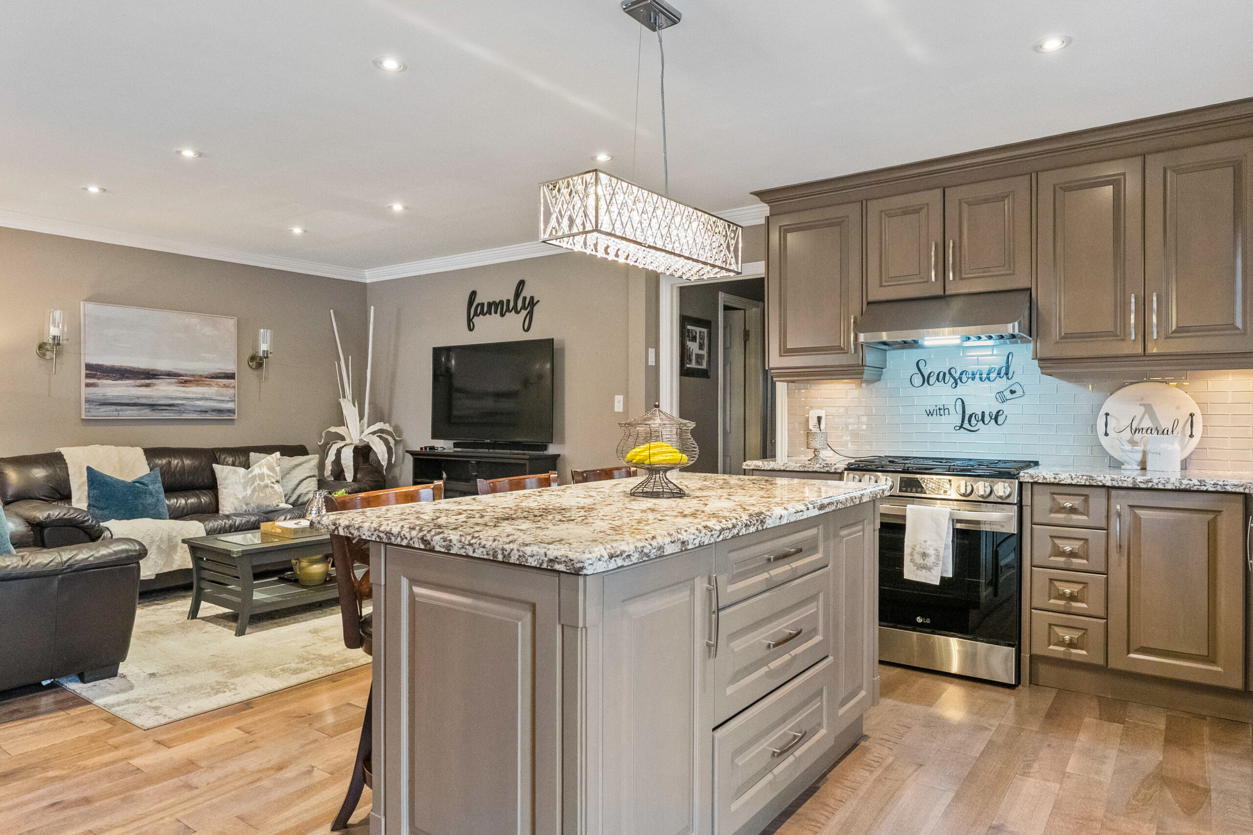 Modern kitchen with granite island, pendant lighting, and cozy living area