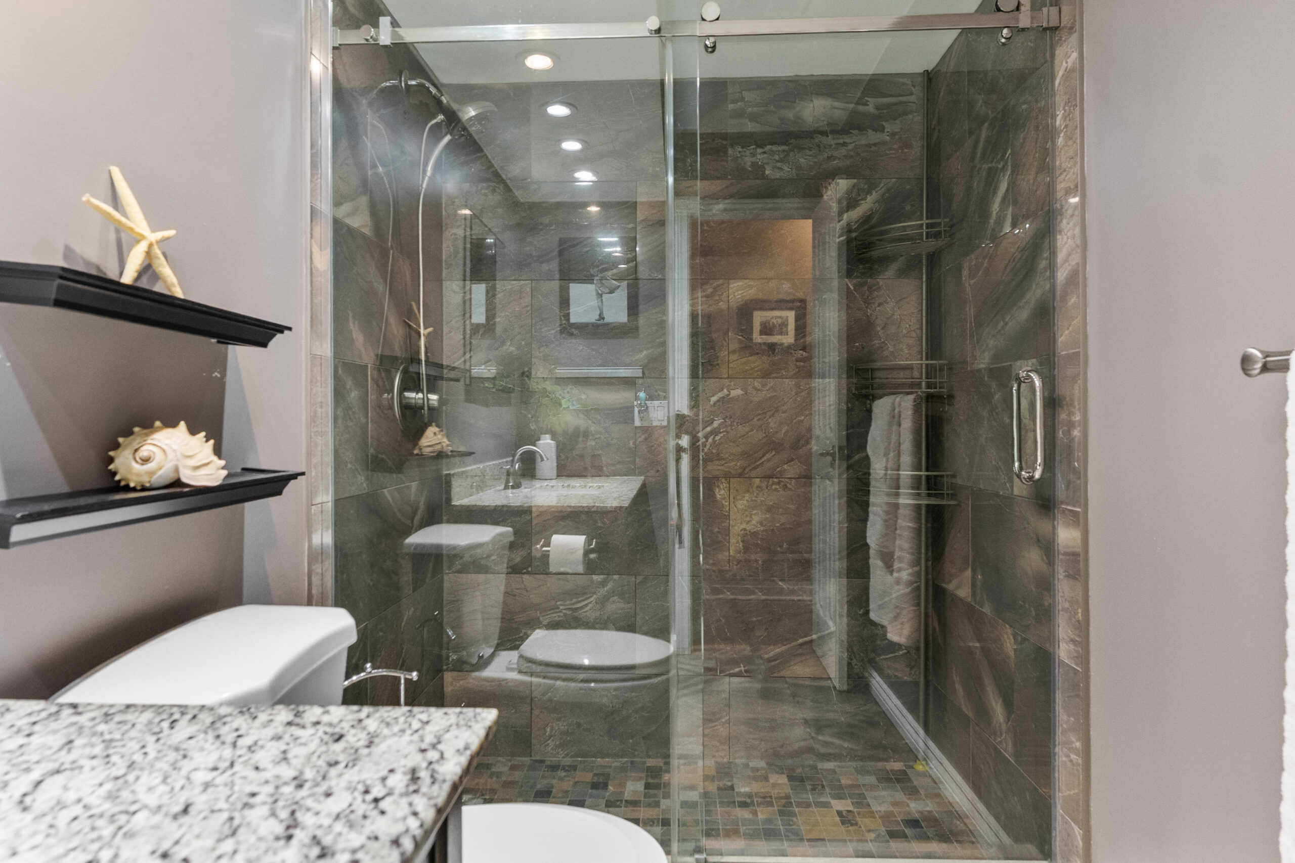 Modern bathroom featuring a glass shower and granite countertop