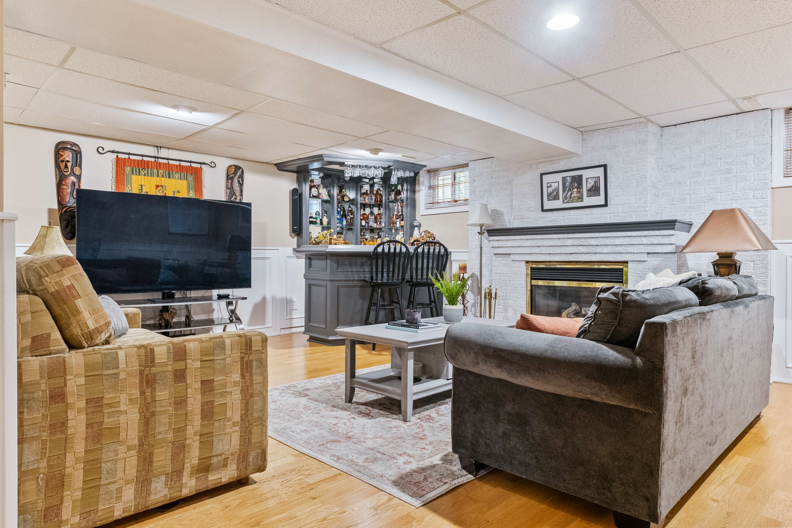 Cozy basement living area with a TV, bar, and comfortable seating