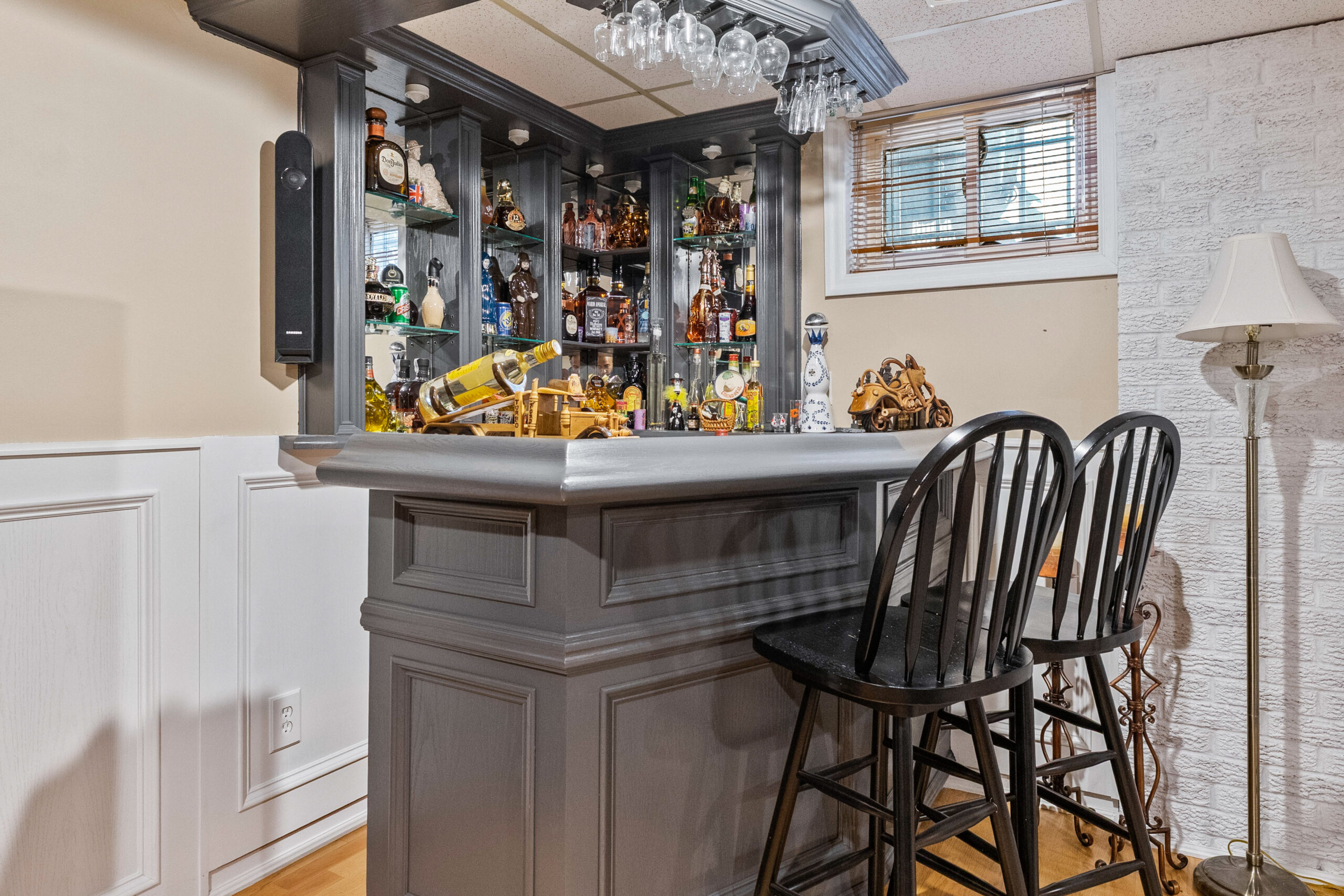Home bar with black chairs, shelves of liquor, and a lighted display