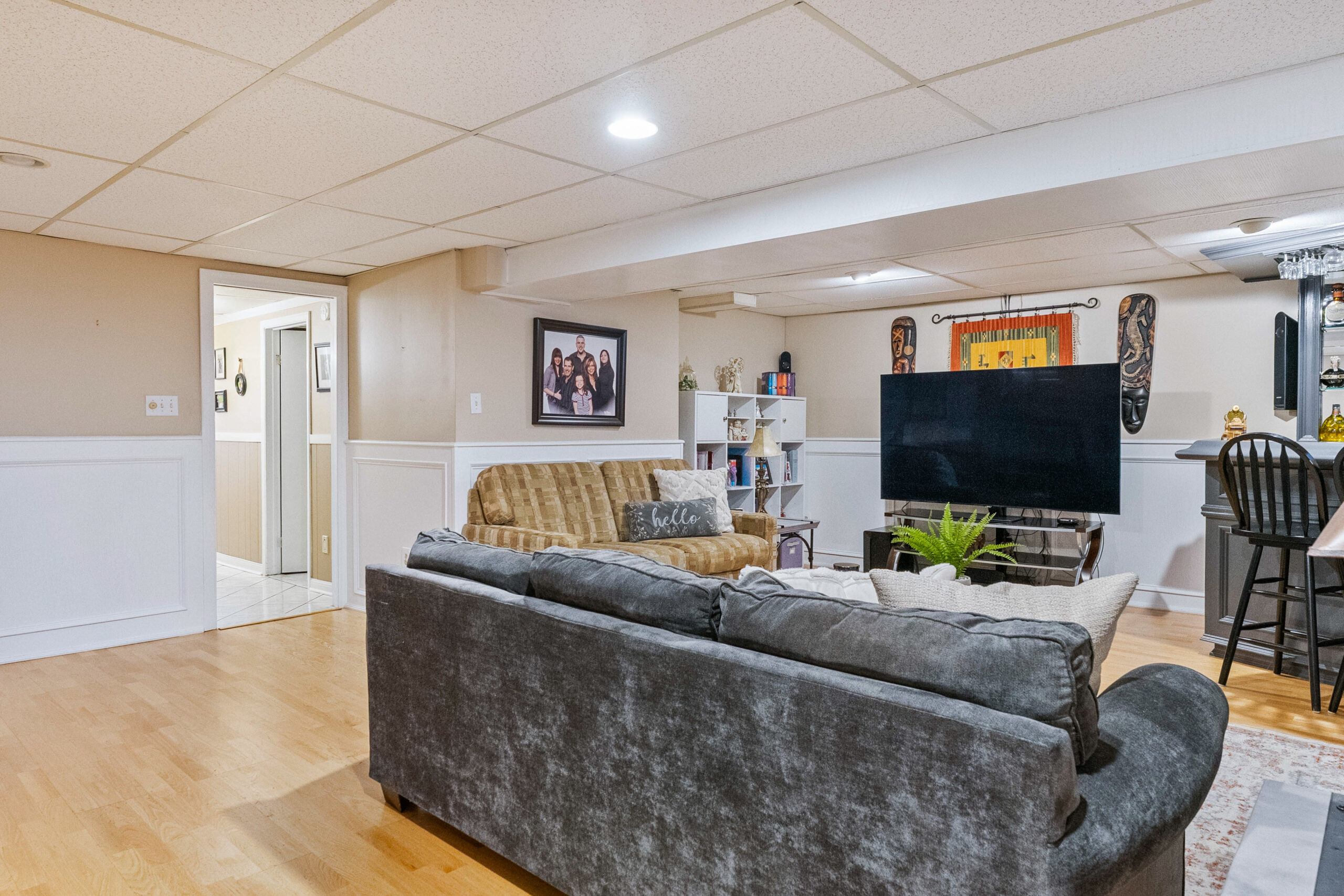 Cozy basement living area with a gray couch and TV, featuring wooden flooring