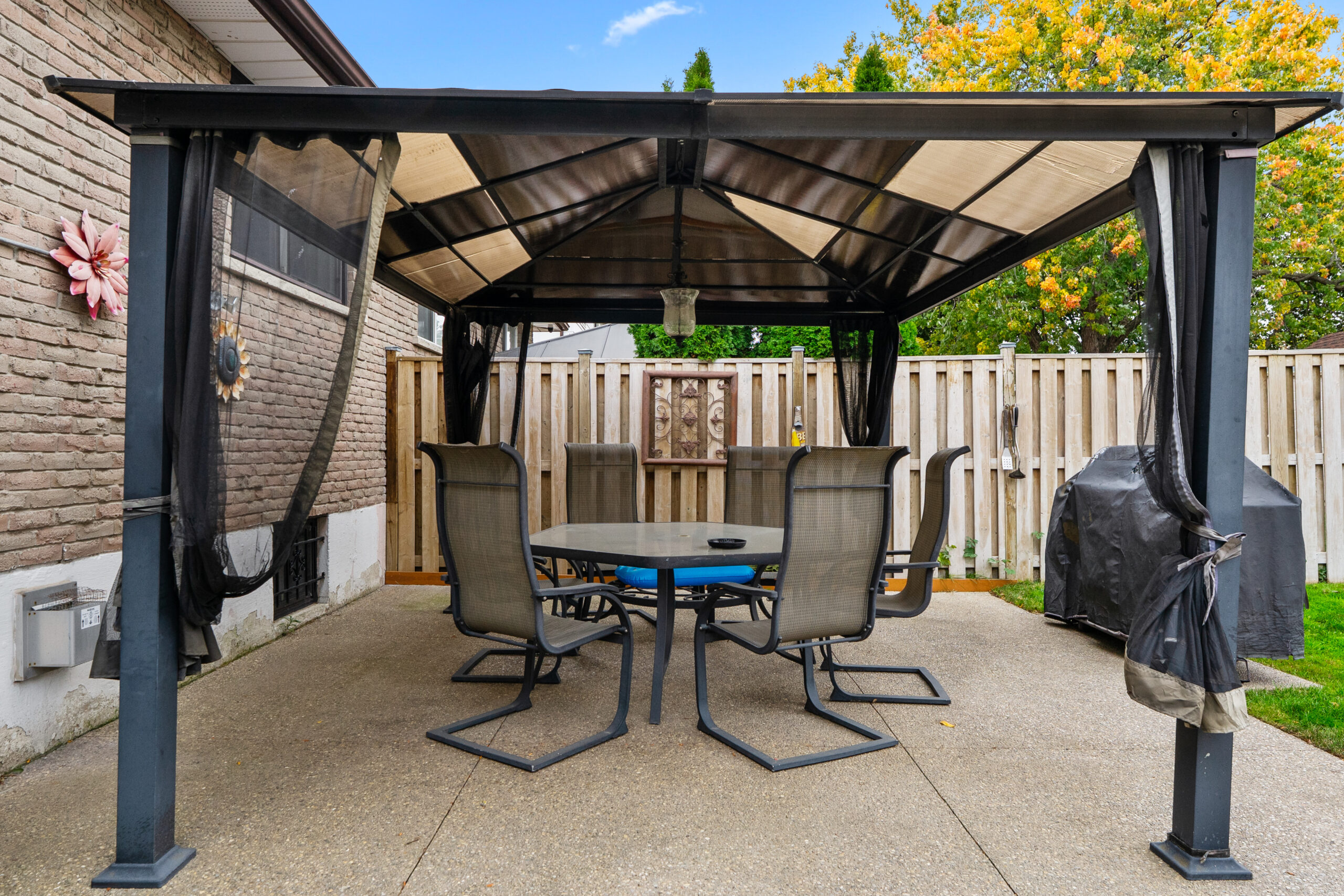 Covered patio with a table and chairs, surrounded by a wooden fence