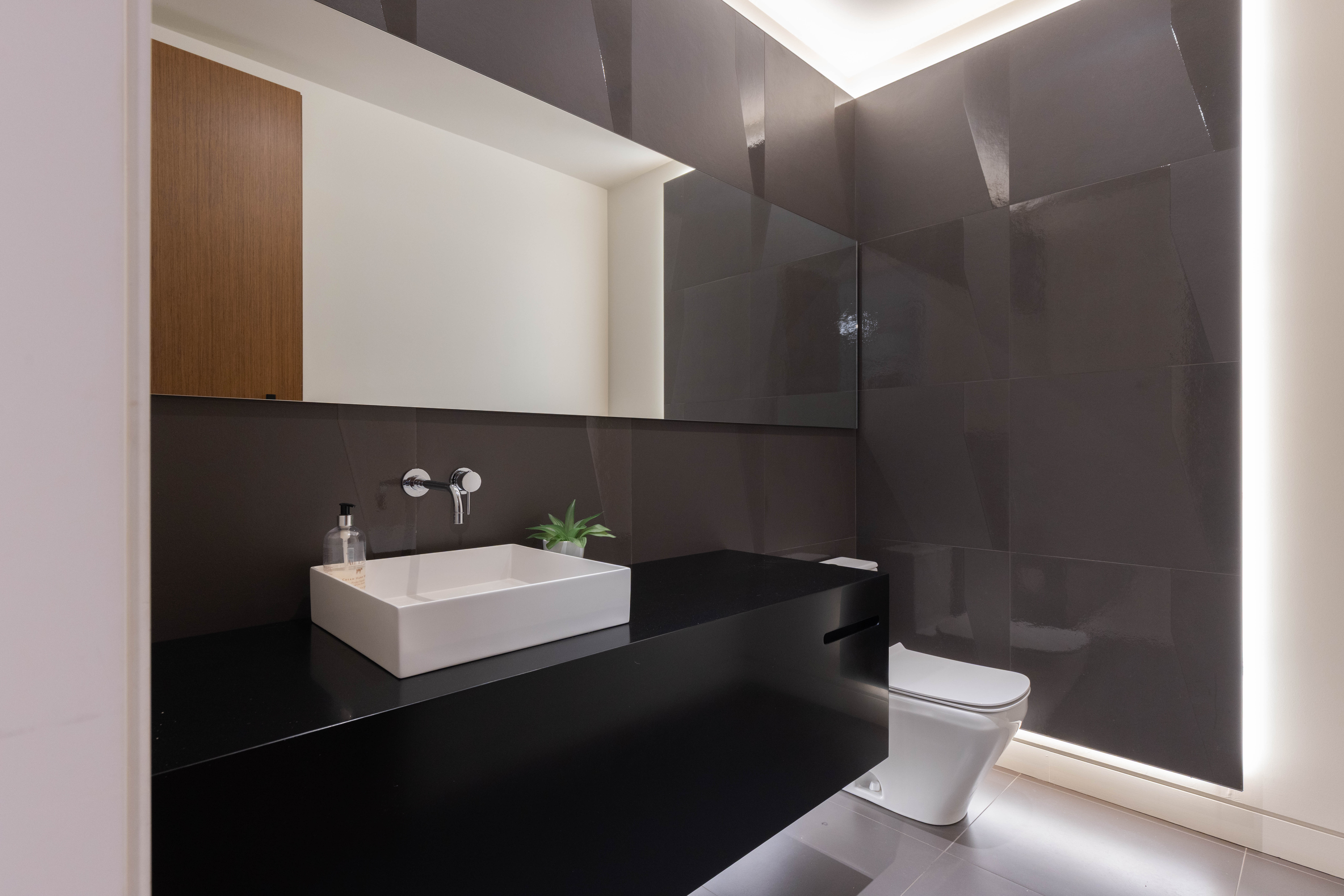 Modern bathroom with dark walls, sleek sink, and minimalist design