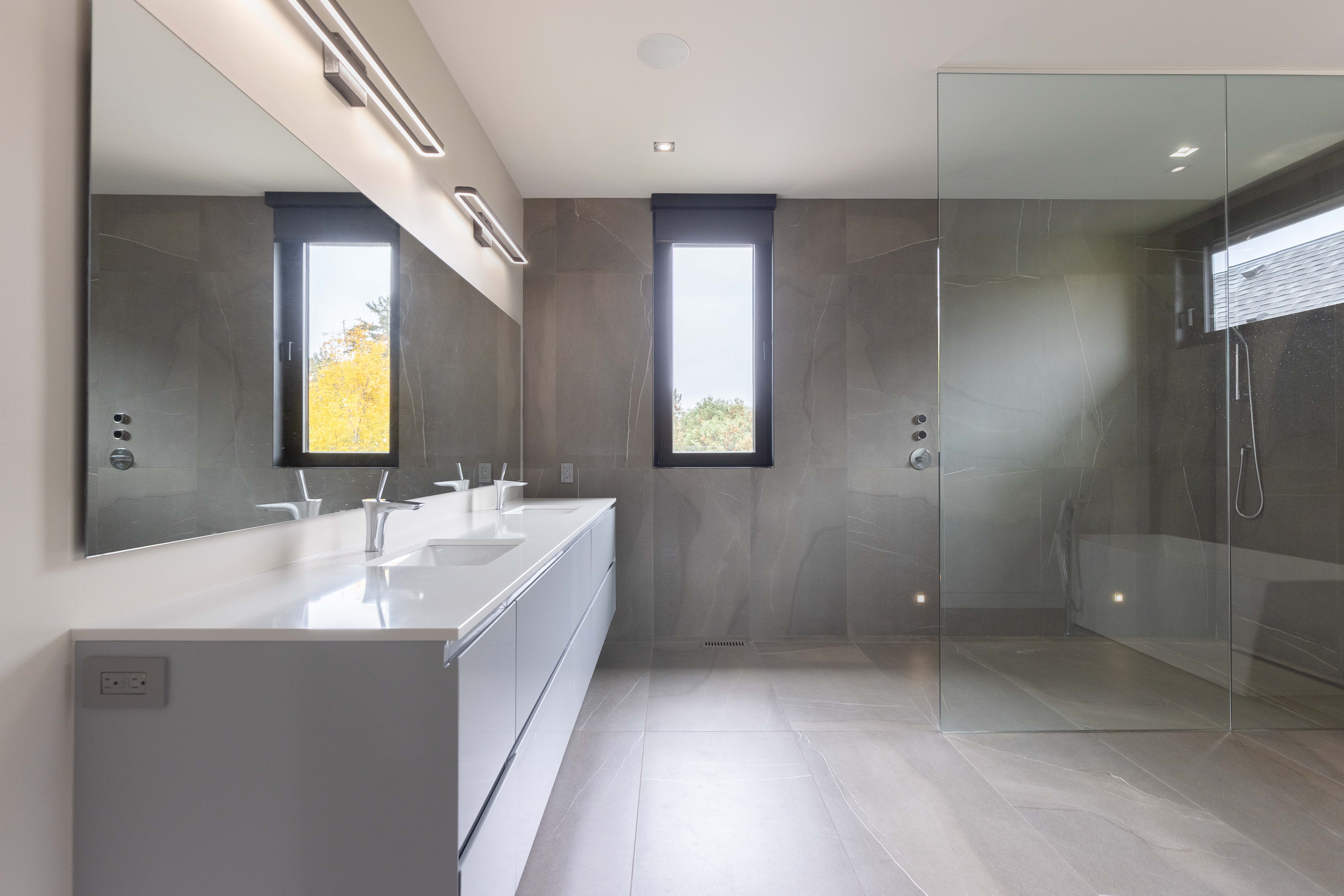 large ensuite with floor to ceiling tiles. glass shower and double vanity