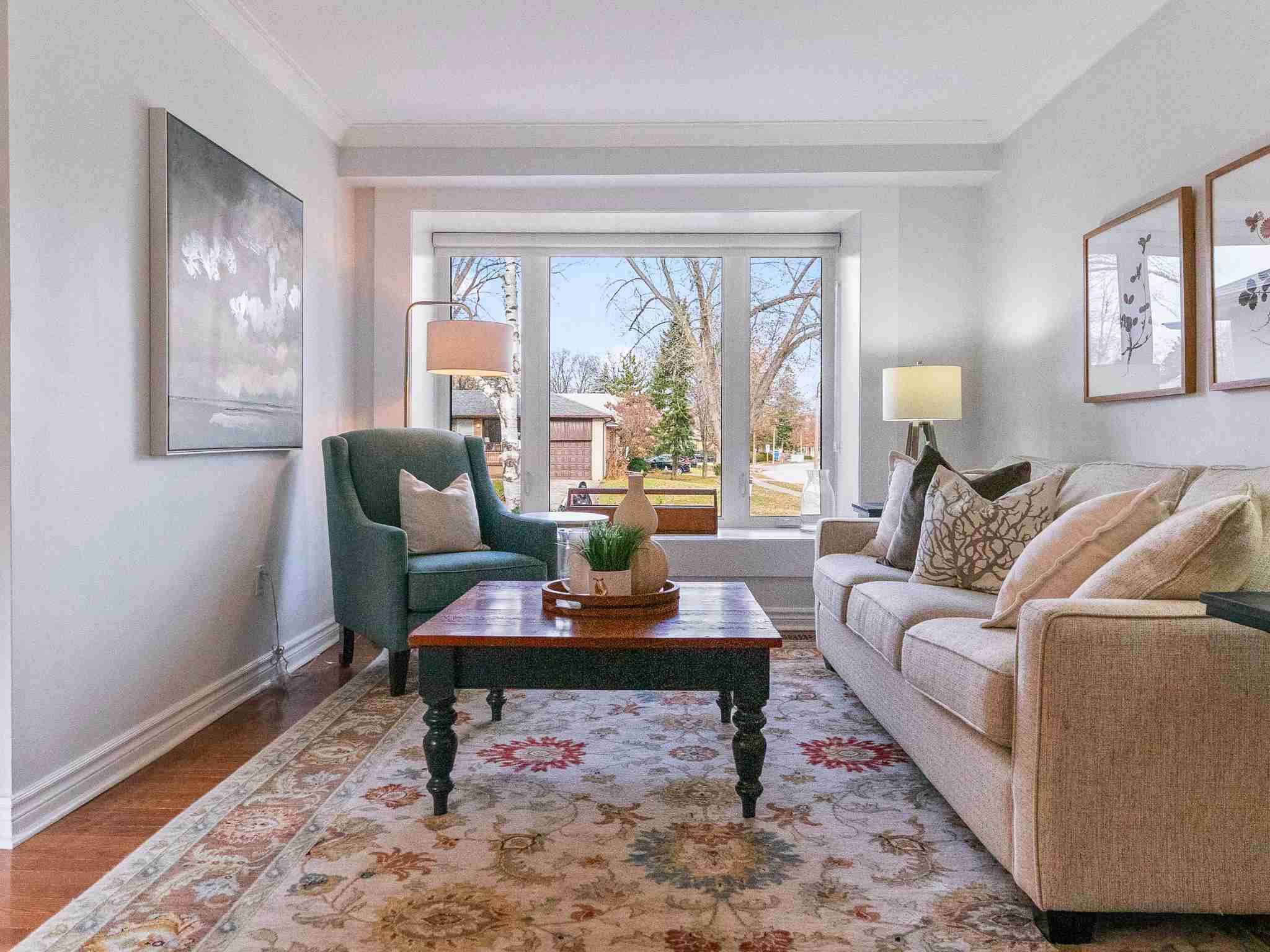 Living room with hardwood flooring and large window facing the street