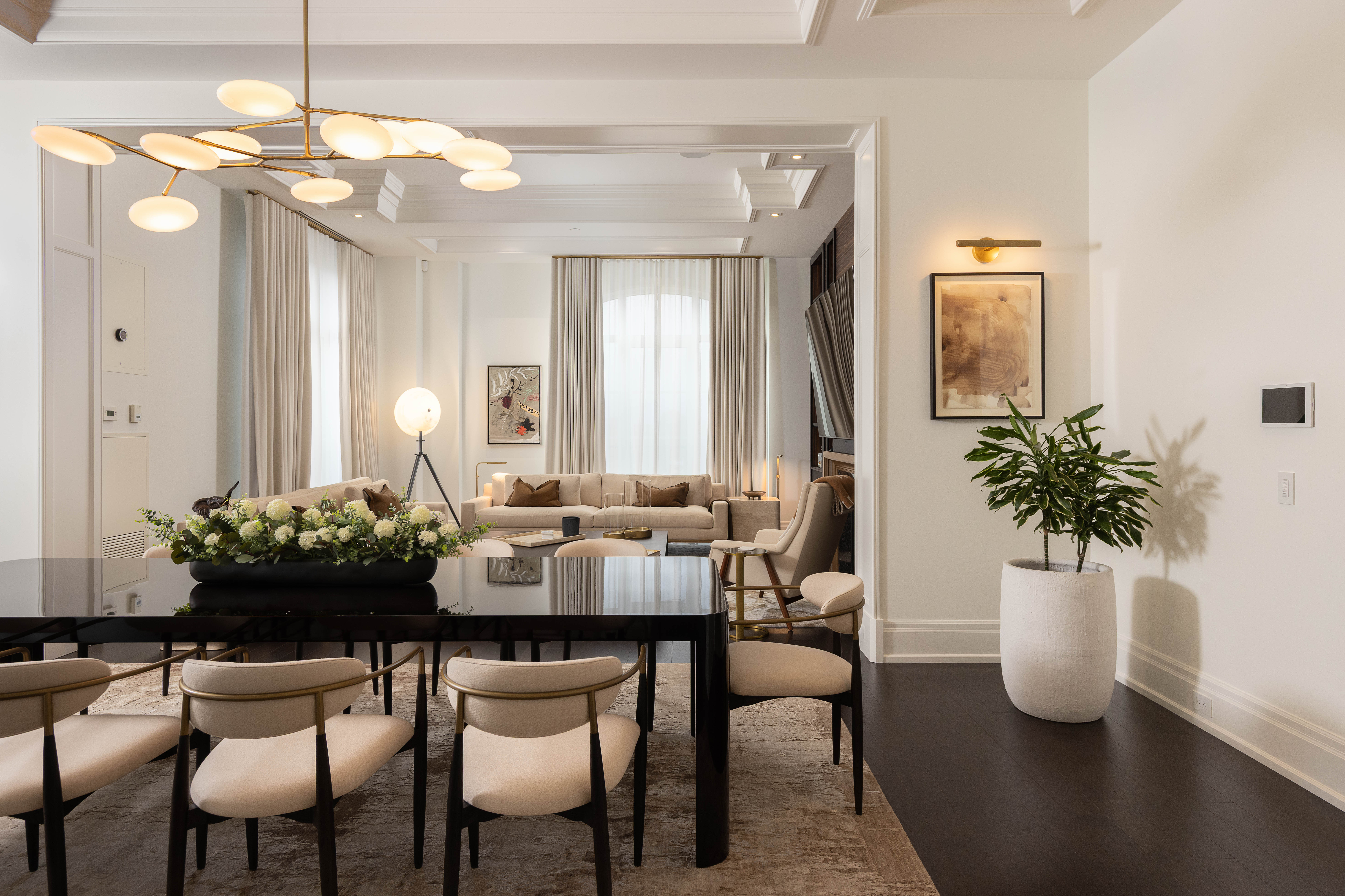 Modern dining area with a black table, beige chairs, and a cozy living space.