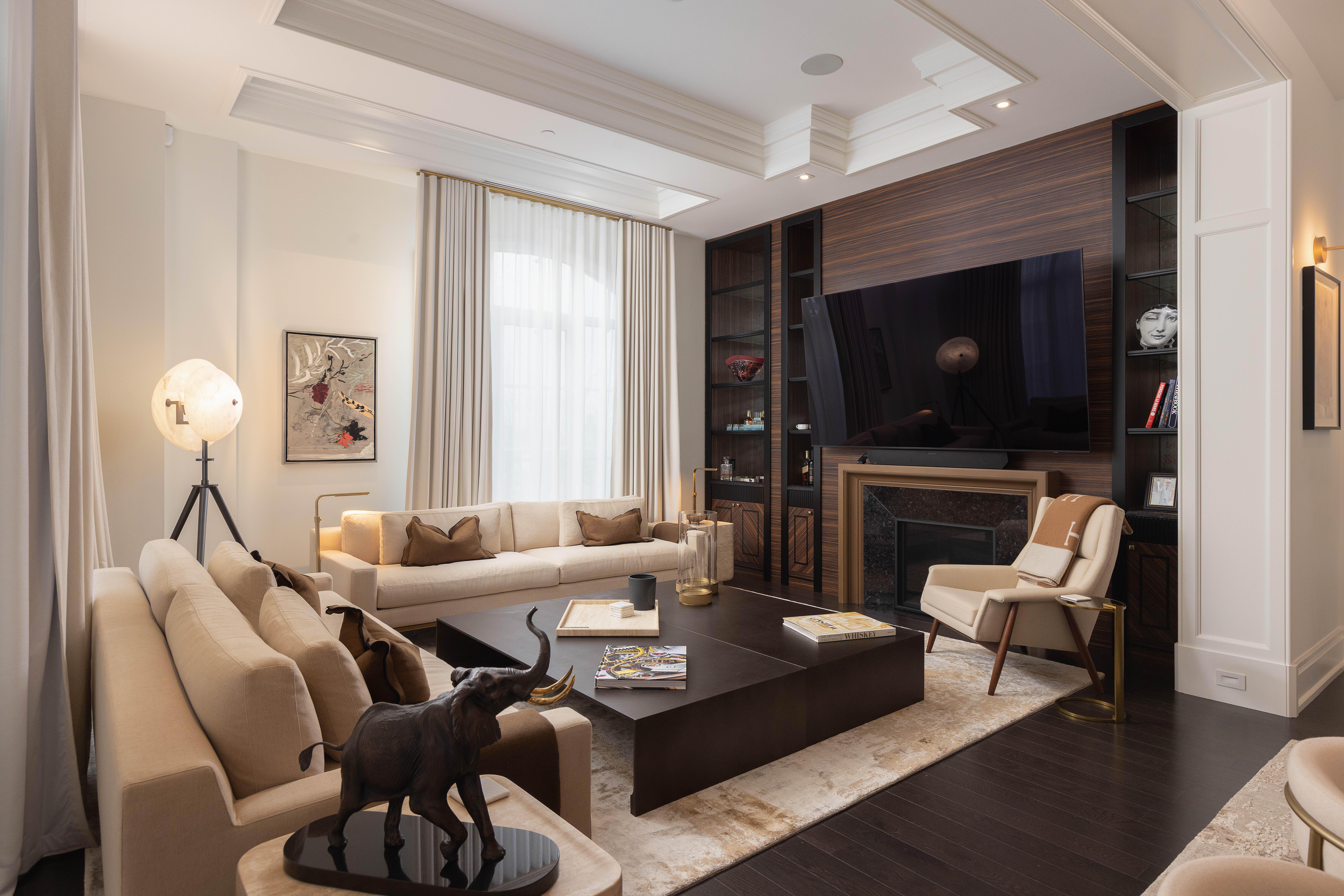 Modern living room with beige sofas, dark wood accents, and a large TV.