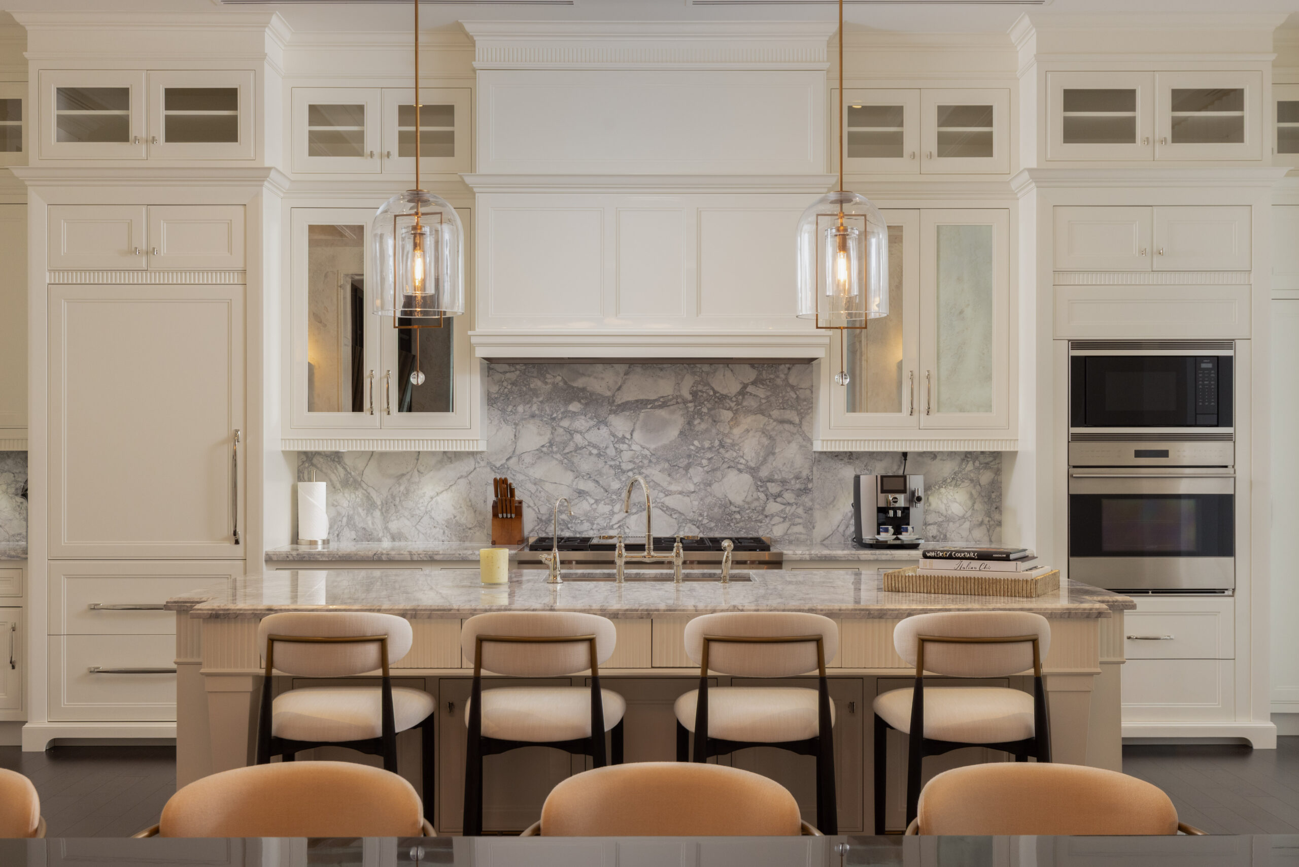 Modern kitchen with white cabinetry, marble backsplash, and bar stools