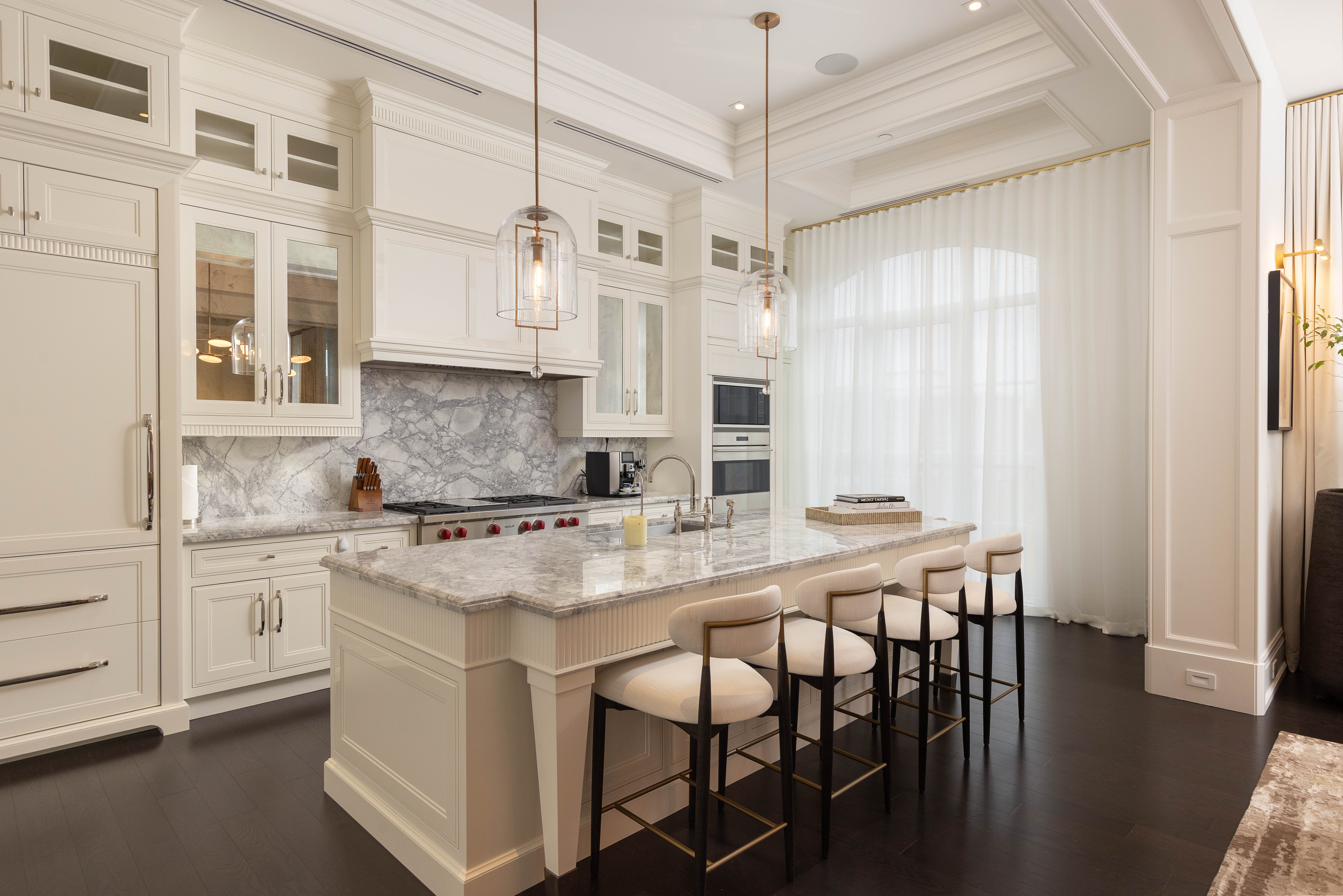 Modern kitchen with white cabinetry, marble countertops, and pendant lighting