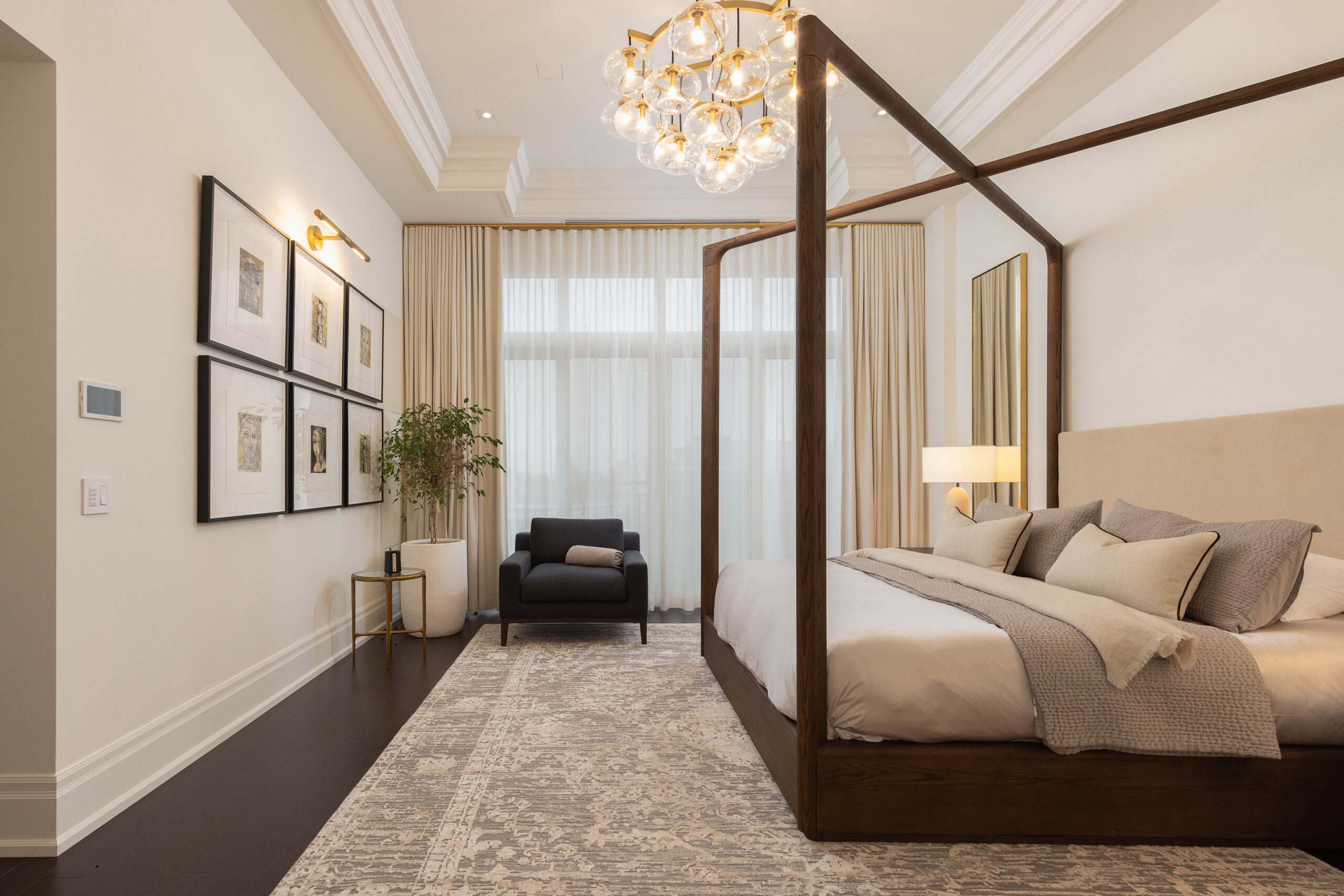 Elegant bedroom with a four-poster bed, armchair, and chandelier