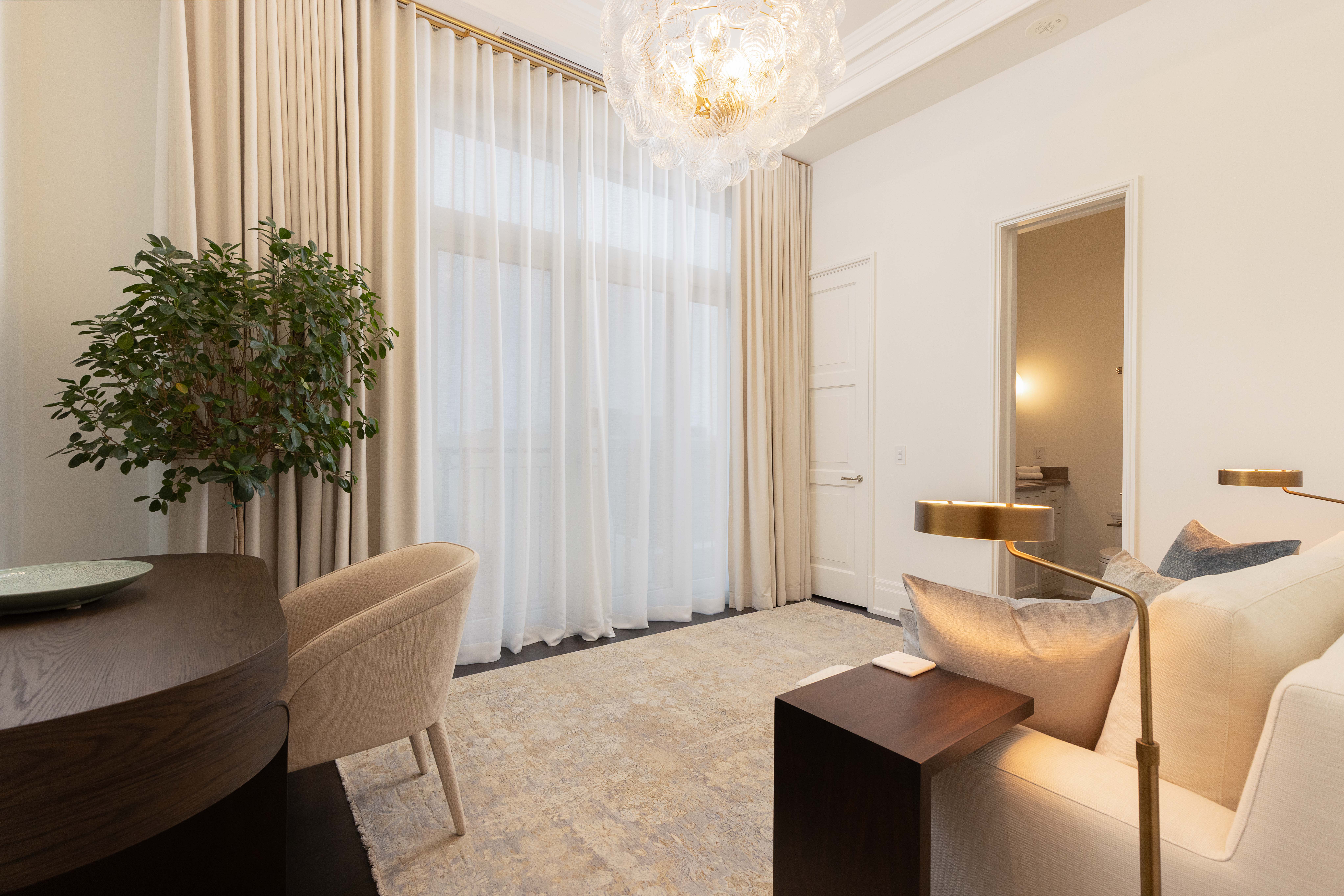 Modern living room with large windows, light curtains, and stylish furniture