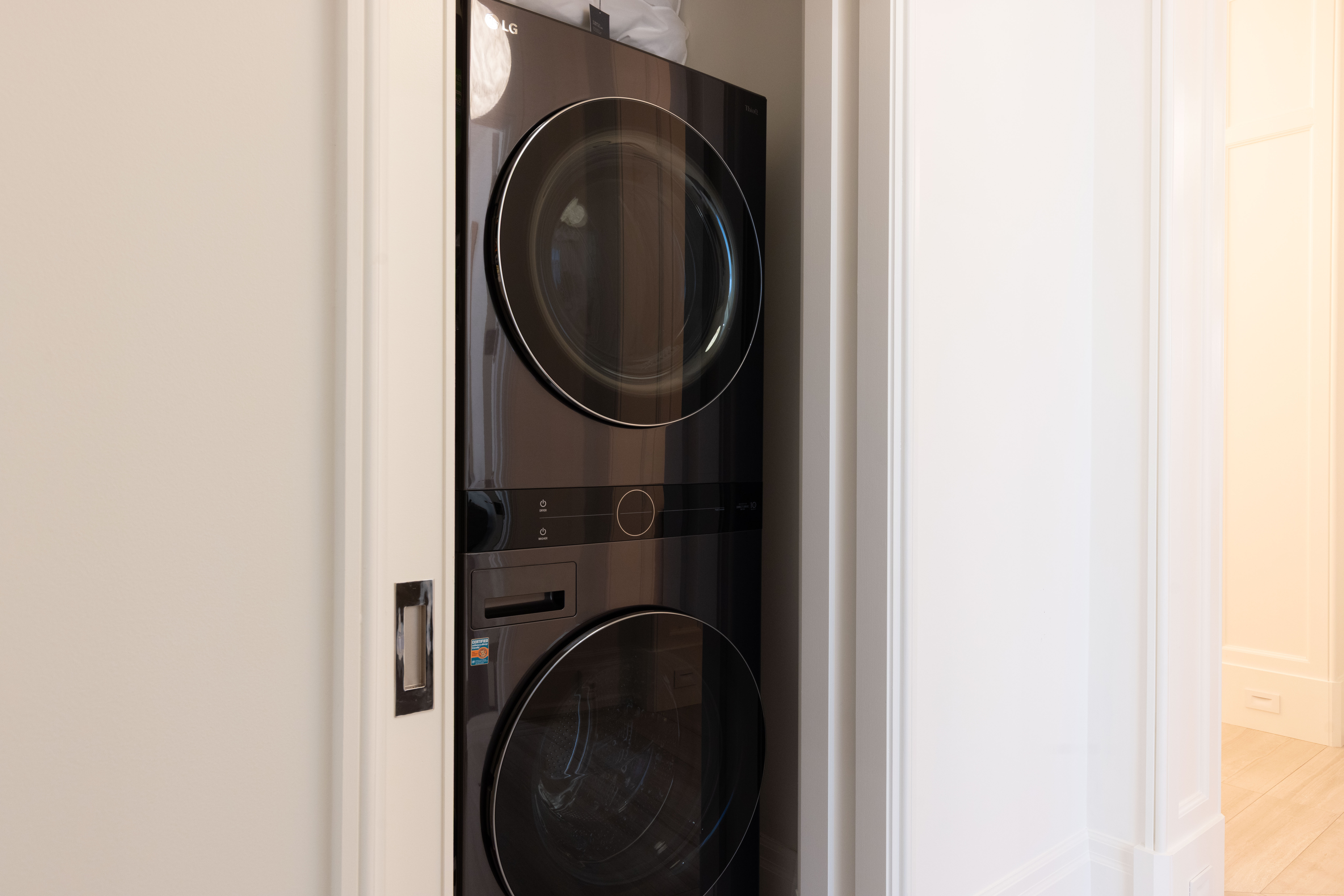Stacked black washer and dryer in a narrow closet space