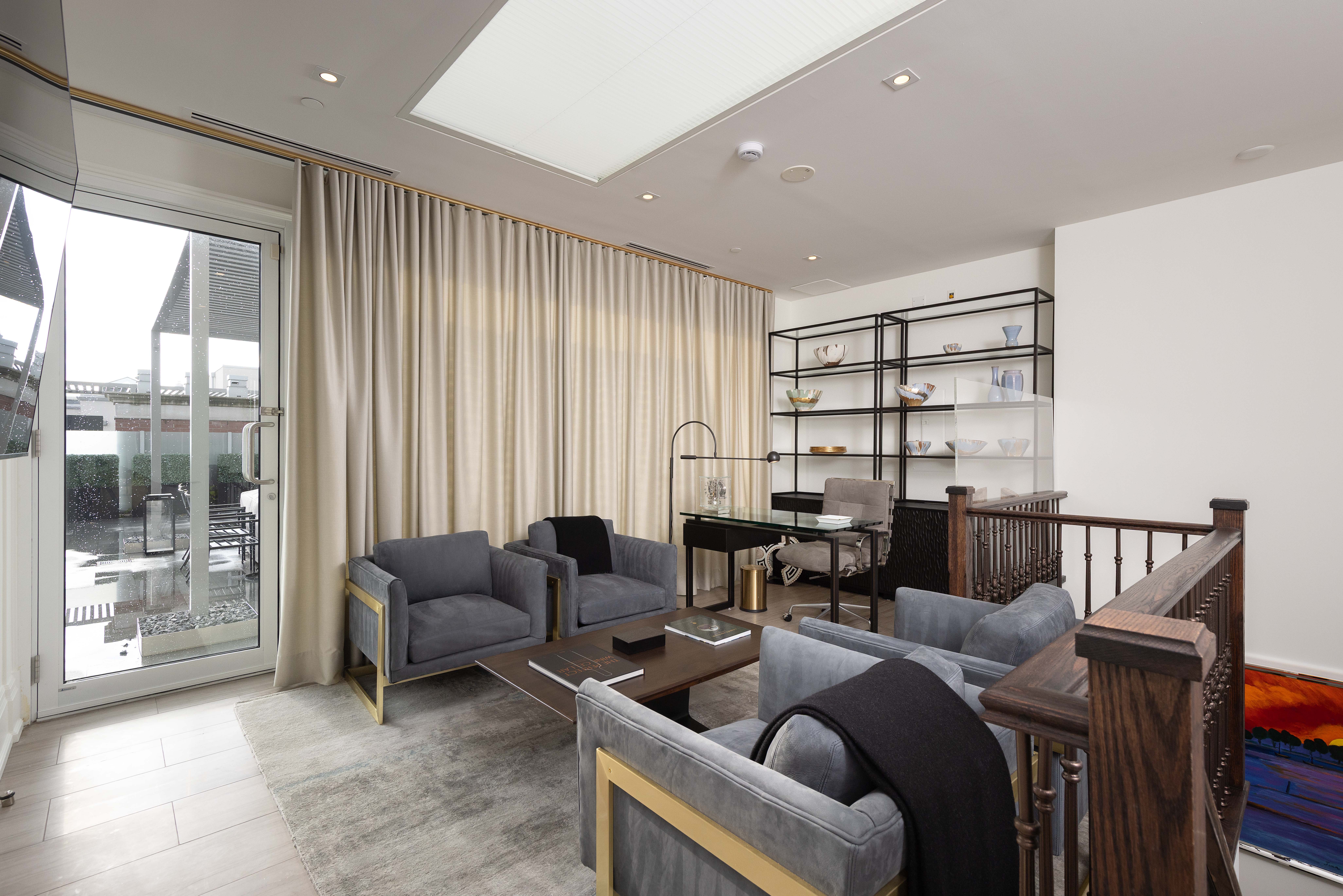 Modern living room with gray sofas, large windows, and stylish shelving unit
