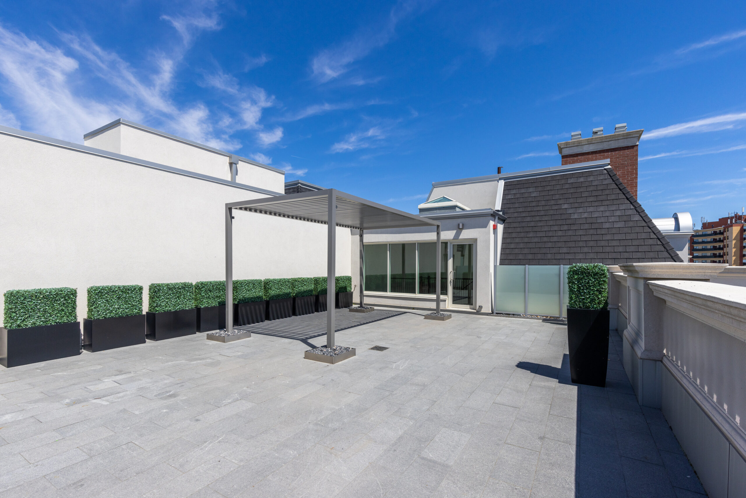 Spacious rooftop terrace with planters and clear blue sky