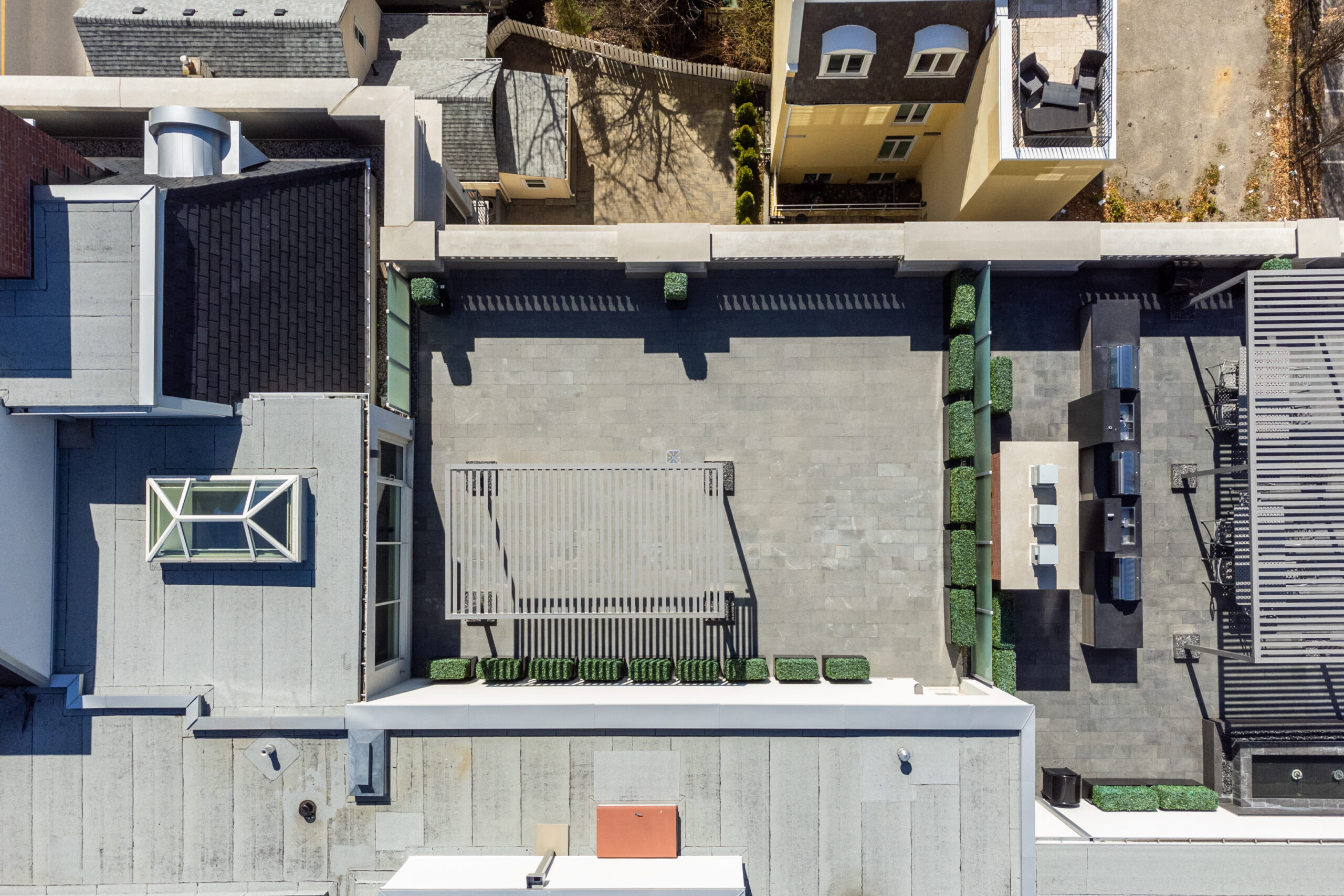 Aerial view of a rooftop terrace with green planters and seating areas