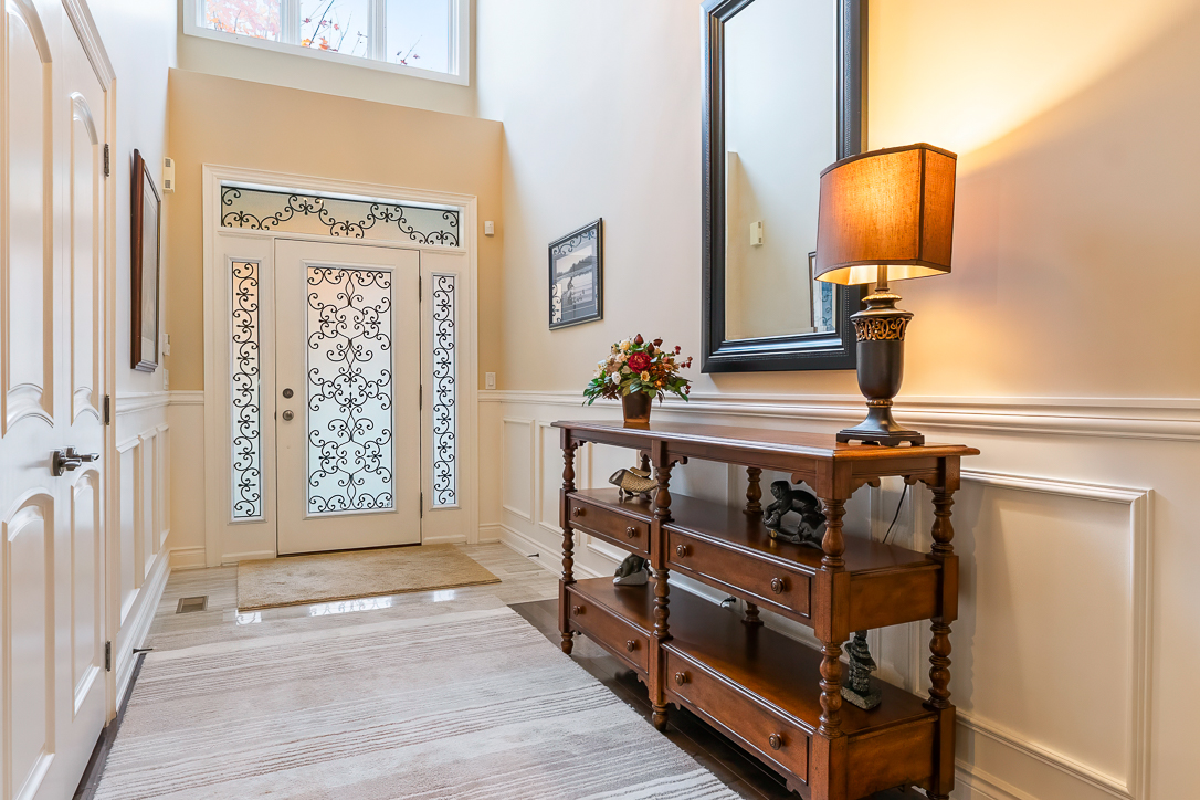 Bright entryway featuring a wooden console table, lamp, and decorative door.