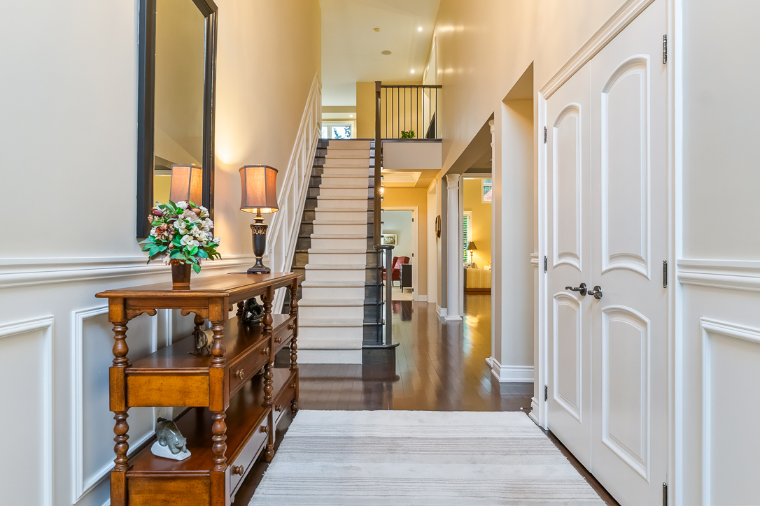 Bright hallway with wooden staircase and console table with flowers