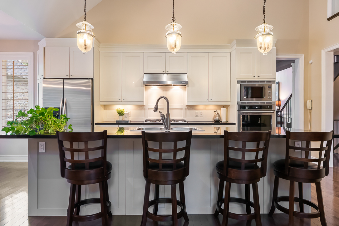 Modern kitchen with white cabinets, bar stools, and pendant lighting