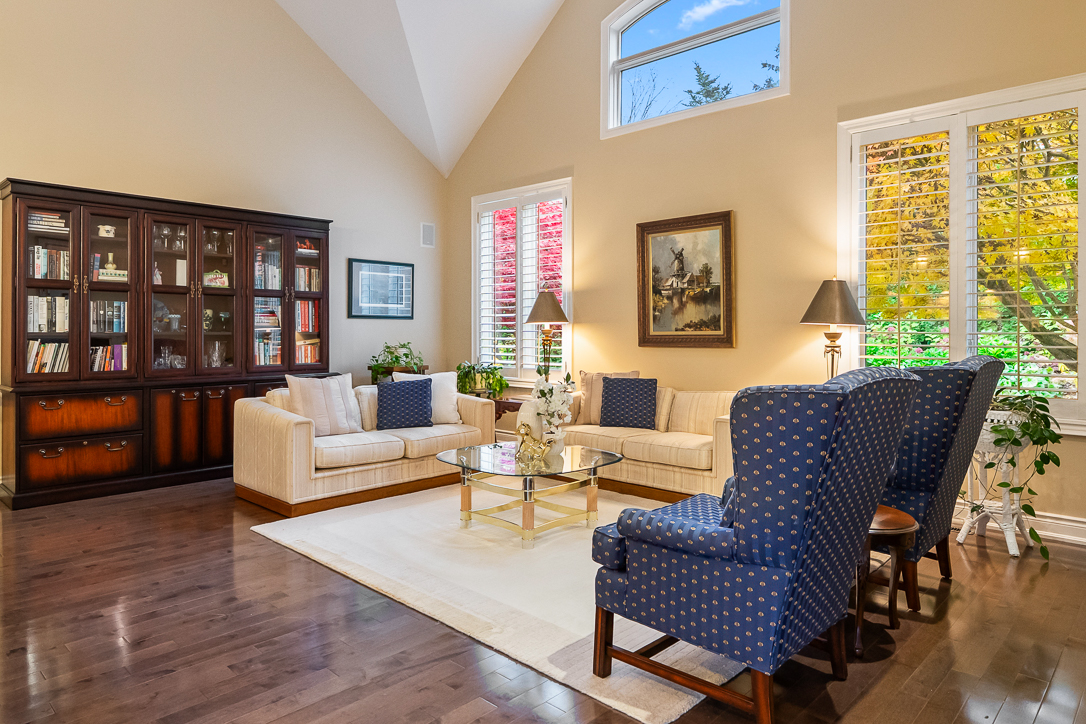 Bright living room with white sofas, blue chairs, and large windows.