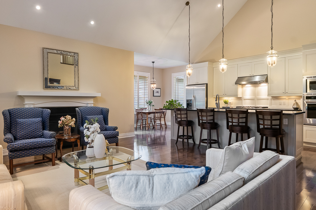 Modern living room with blue chairs, white sofa, and kitchen bar area