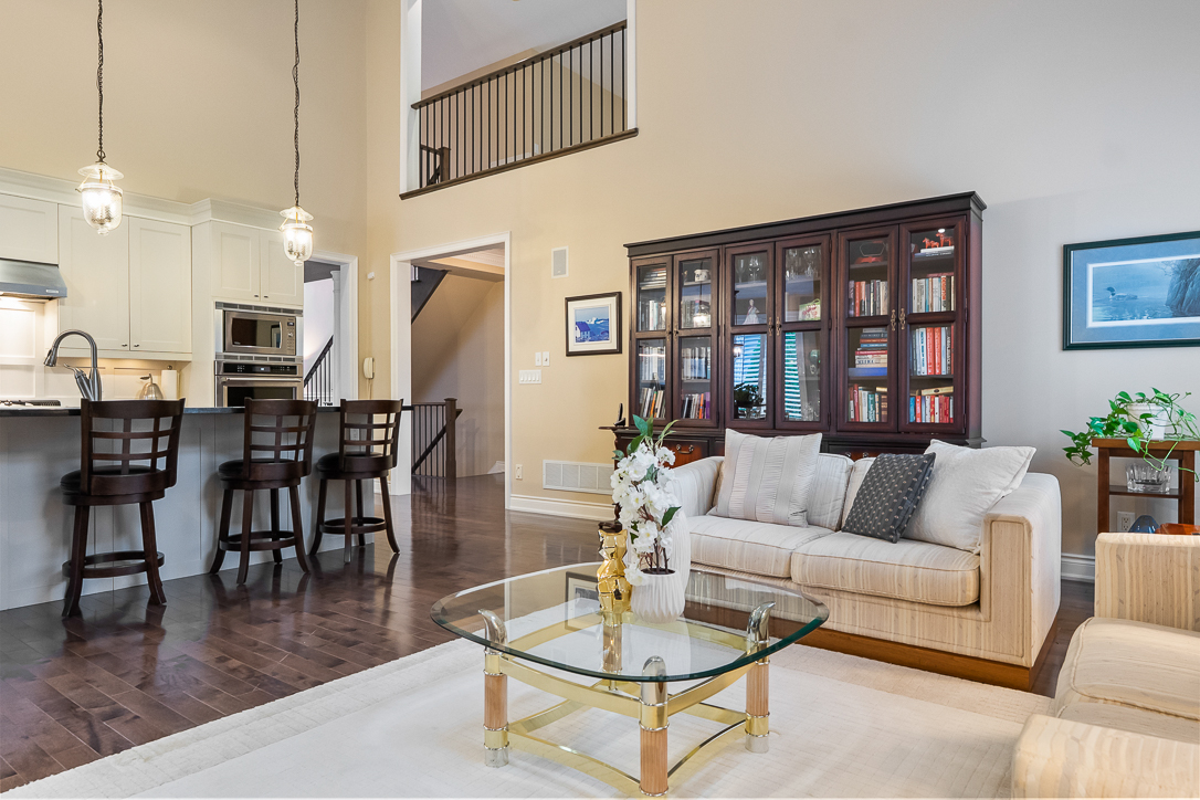 Modern living room with beige sofa, glass coffee table, and dark wood accents