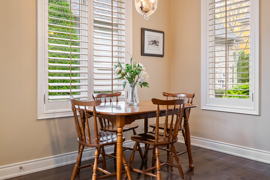 Cozy dining area with a wooden table and four chairs, surrounded by windows